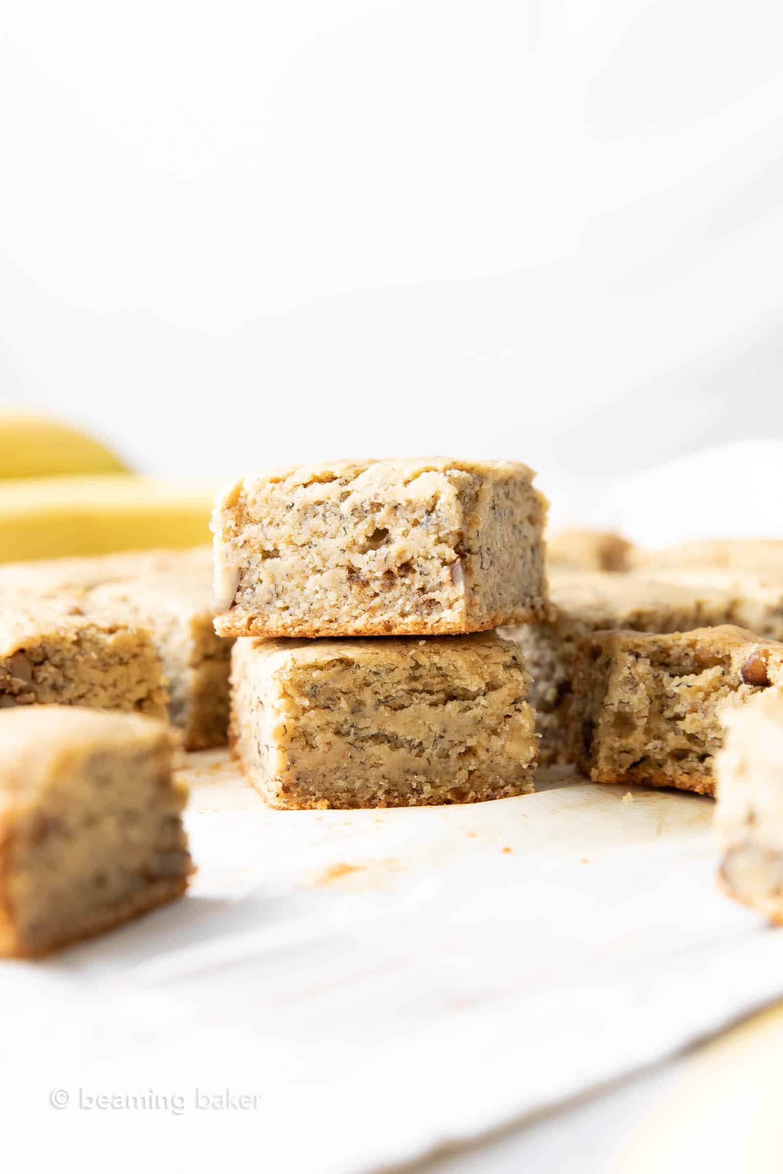far away shot of healthy banana bread bars spread out on table with bananas in background