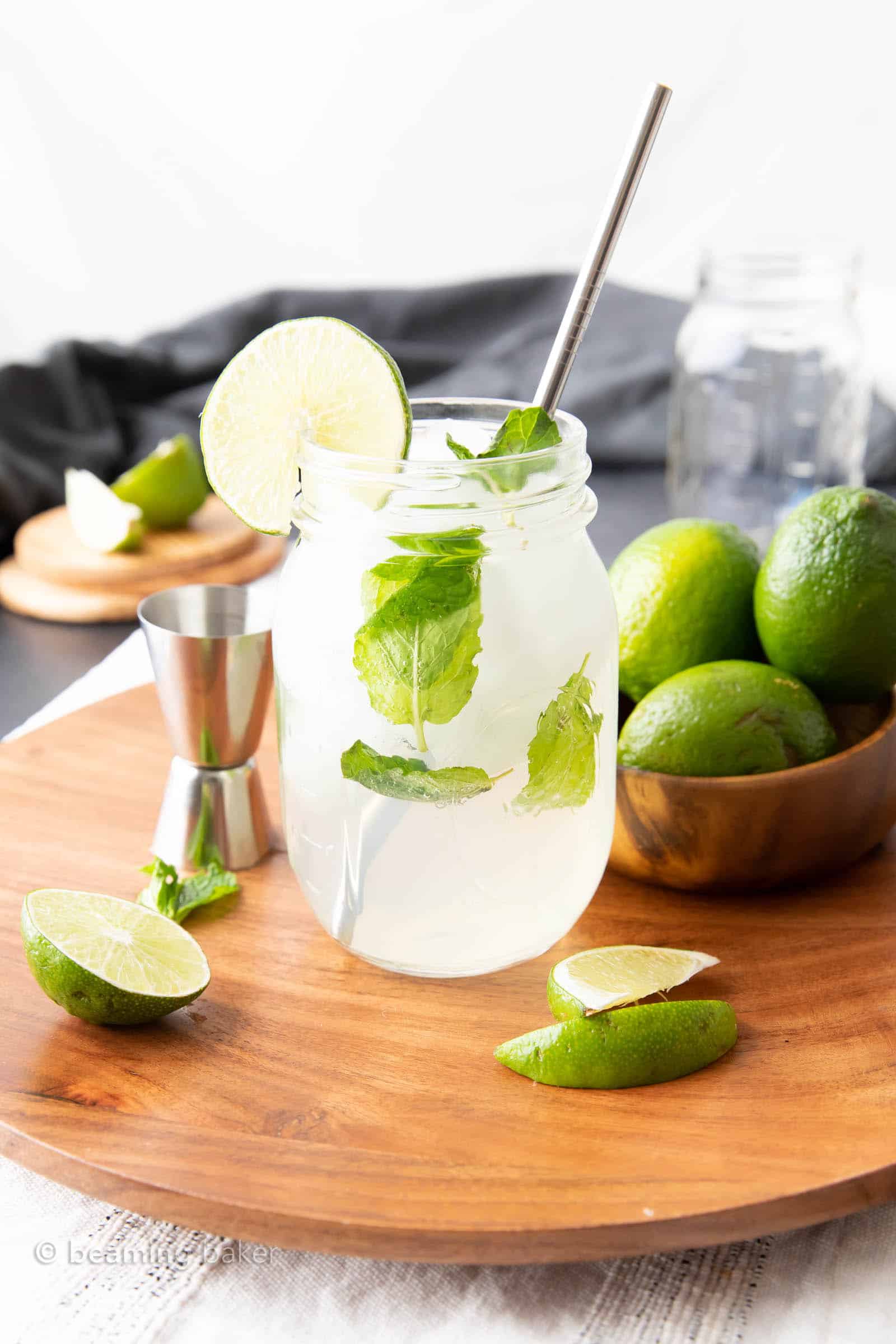 recipe for virgin mojito mocktail in a glass surround by limes