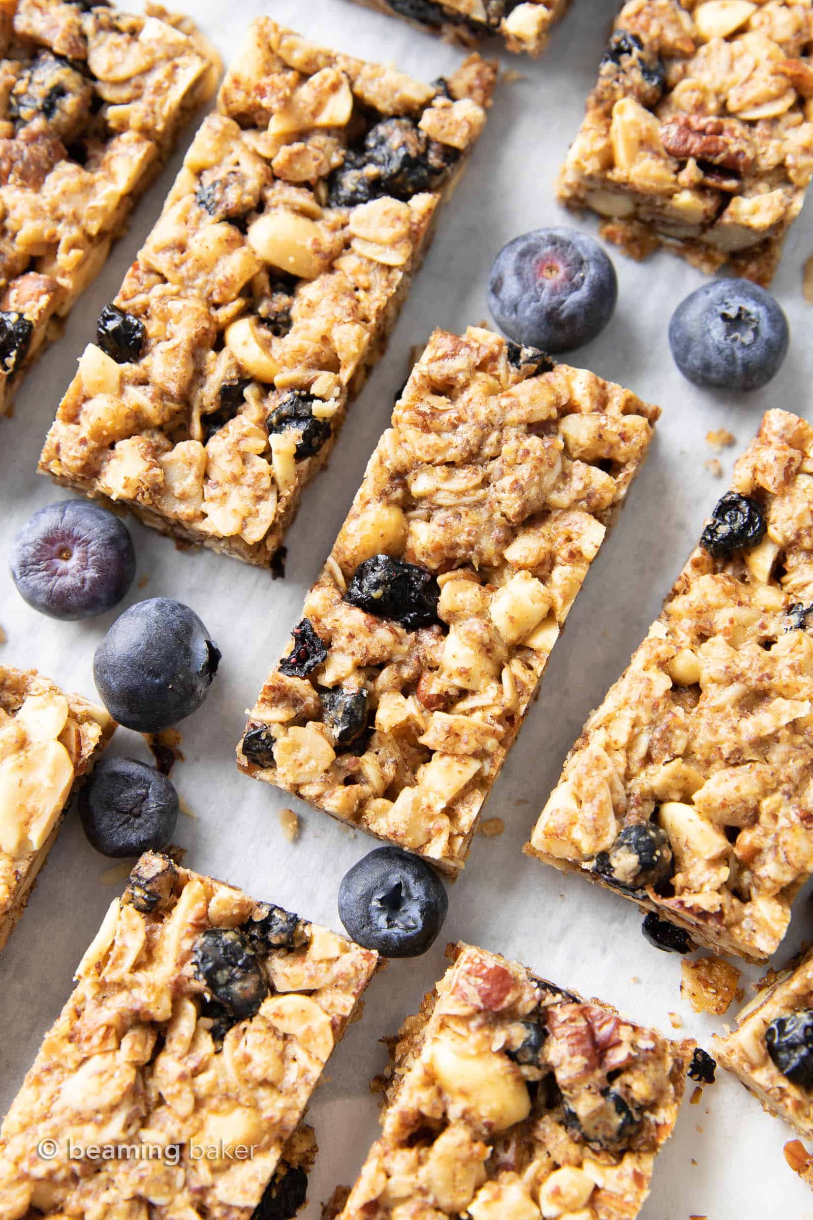 blueberry granola bars spread out on a gray kitchen table with fresh blueberries