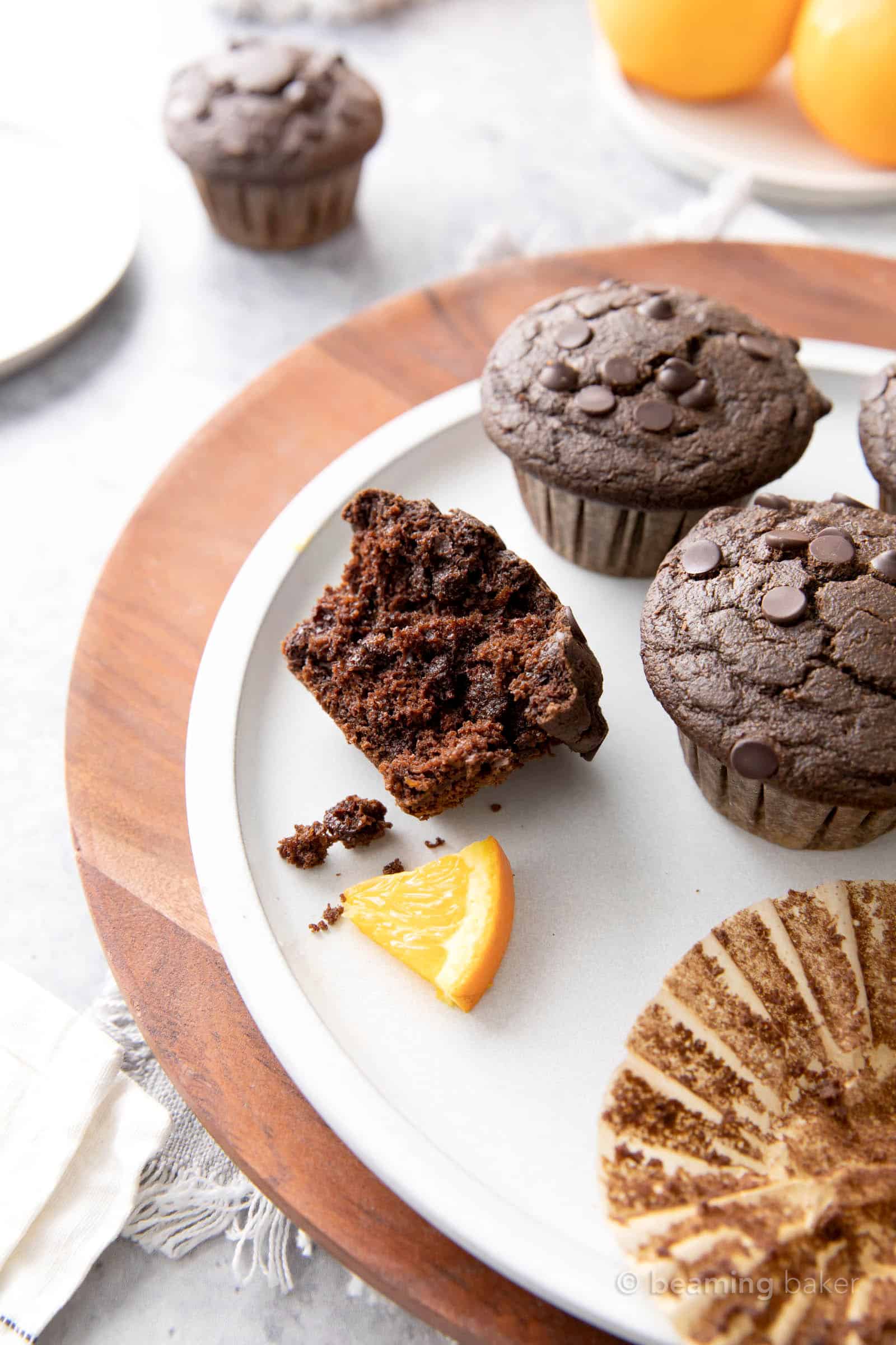A plate filled with orange chocolate chip muffins and orange slices