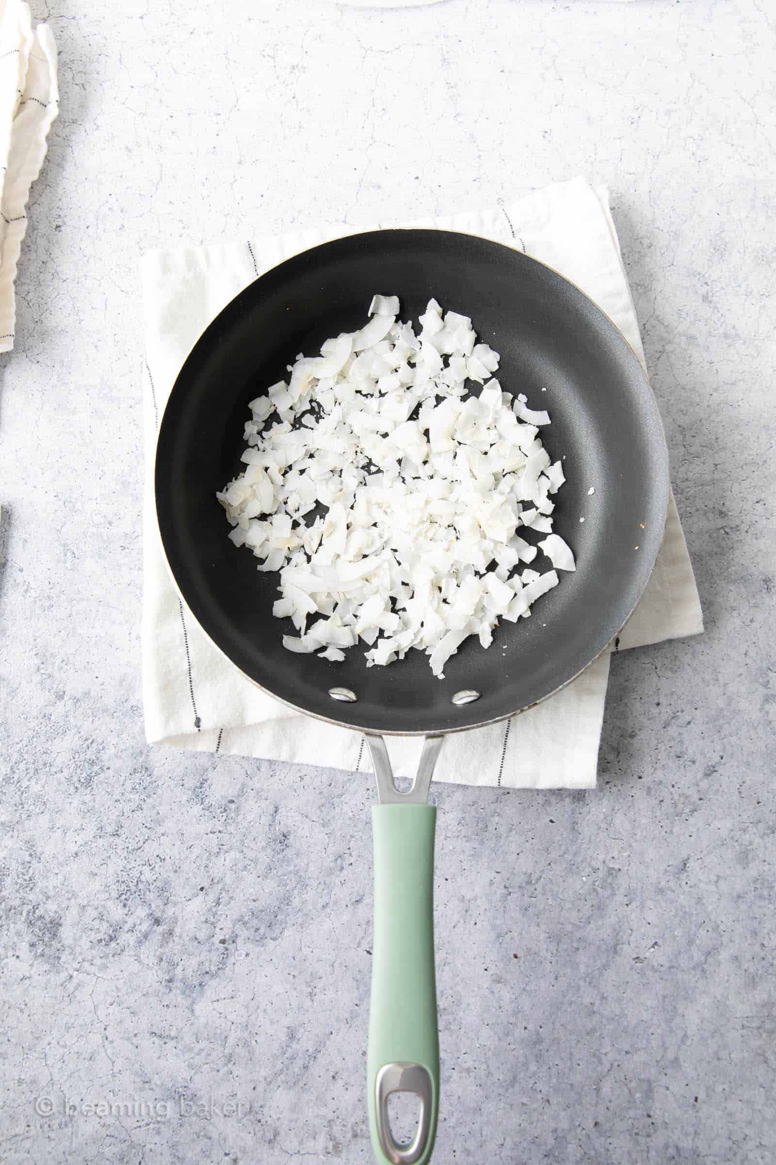 before toasting photo of raw coconut in pan