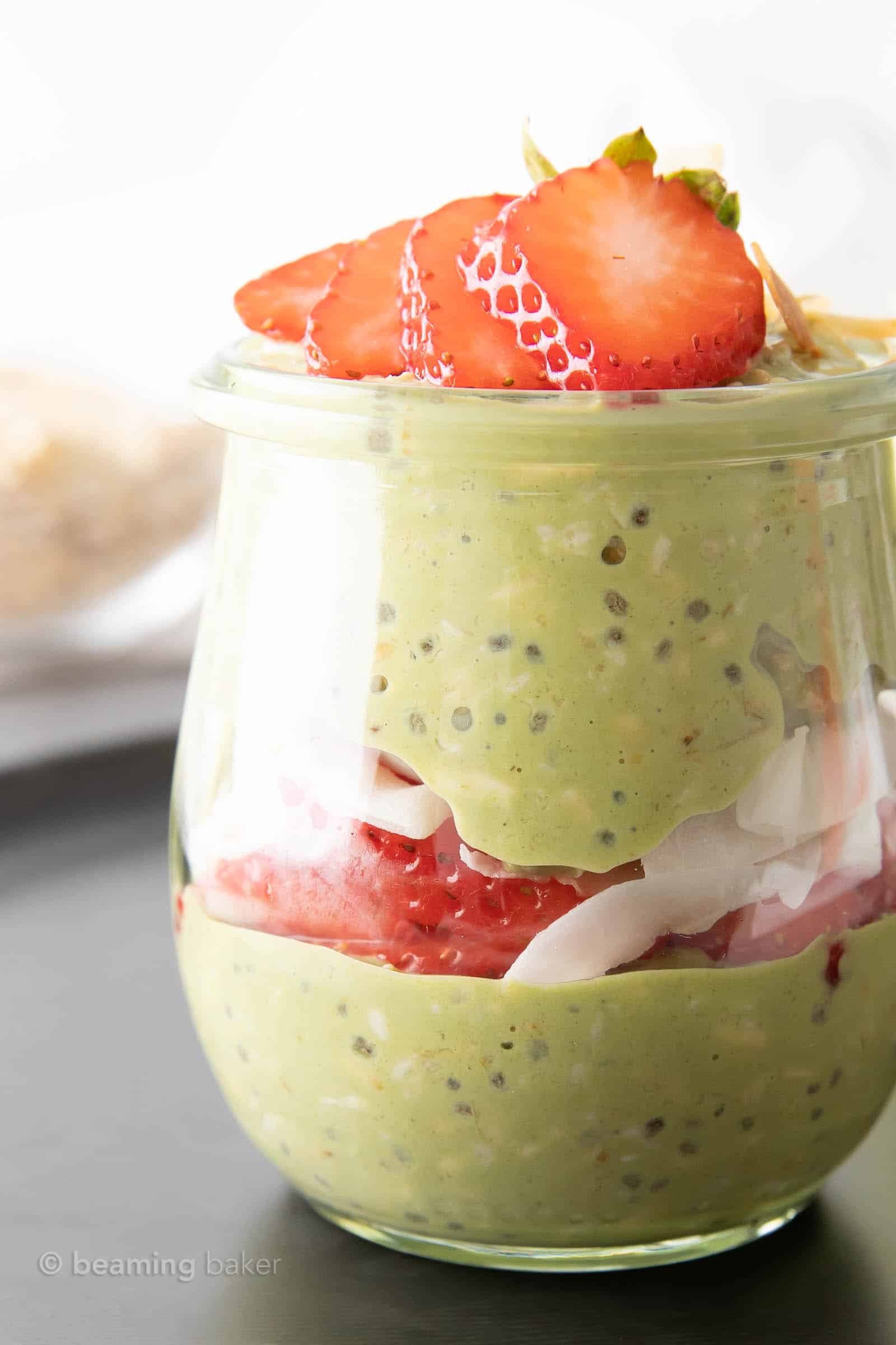super closeup shot of matcha overnight oats layered with strawberries and coconut in a glass jar