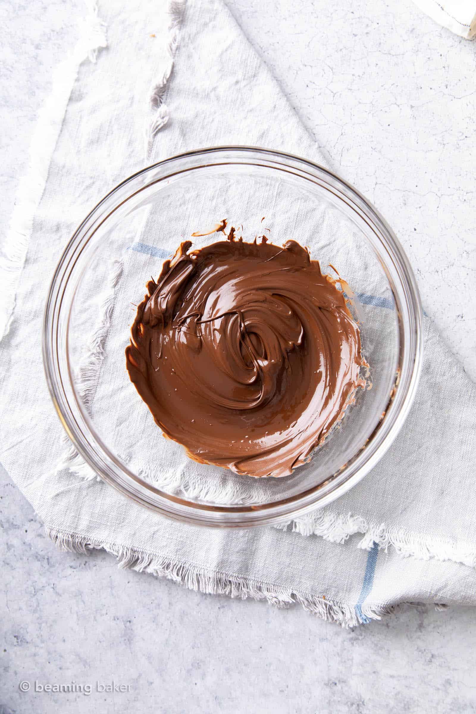 Melted dark chocolate chips smoothed into completely melted chocolate in a glass bowl