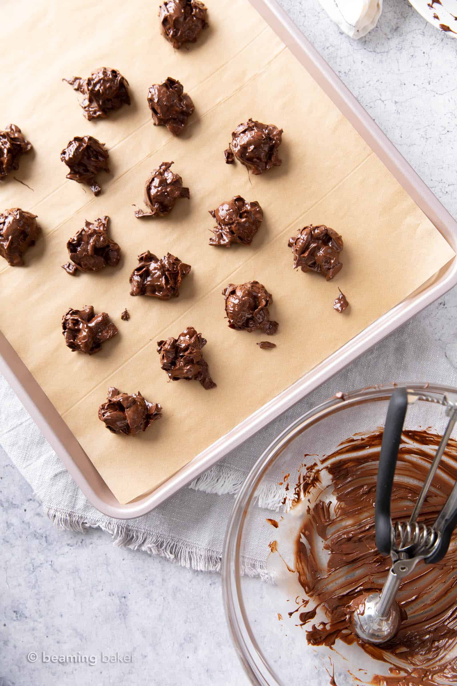 A lined sheet filled with melty dark chocolate coconut almond clusters