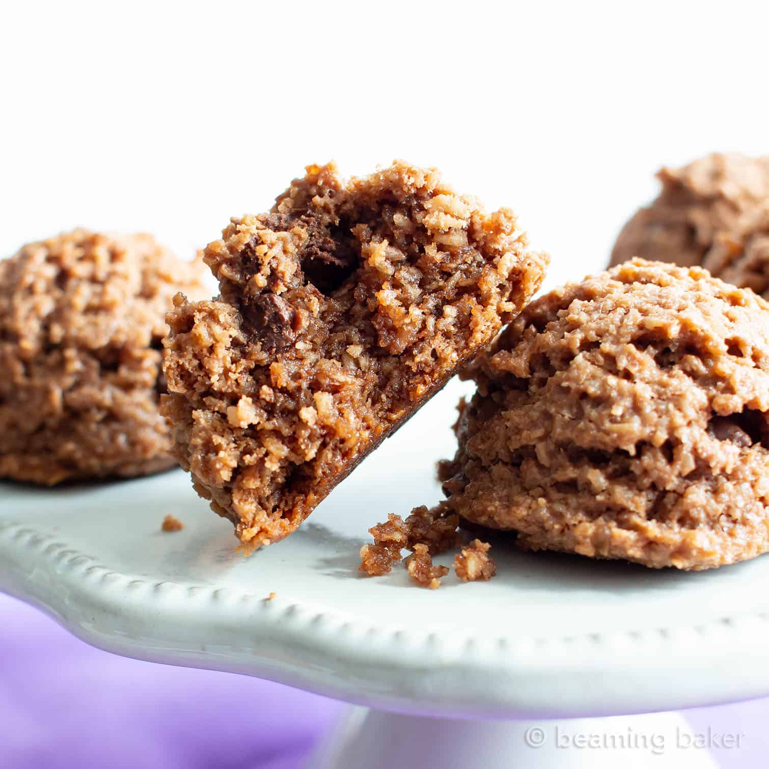 One chocolate keto coconut macaroon split in half resting on a ceramic serving platter