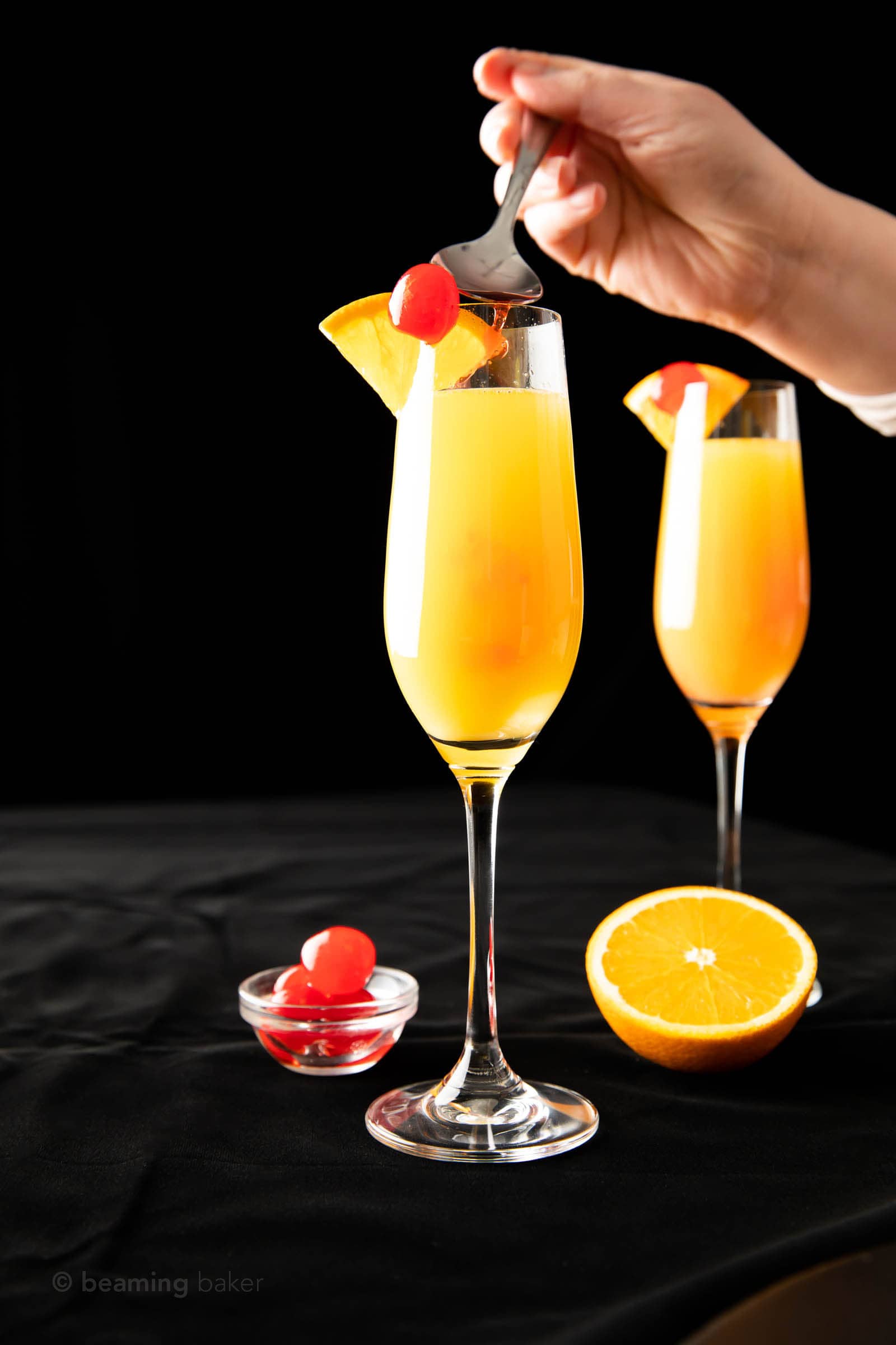 hand spooning grenadine into mimosa to make a sunrise mimosa