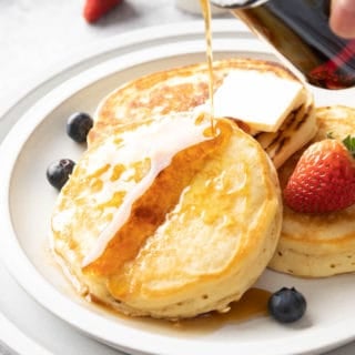 closeup of pouring pure maple syrup onto vegan buttermilk pancakes
