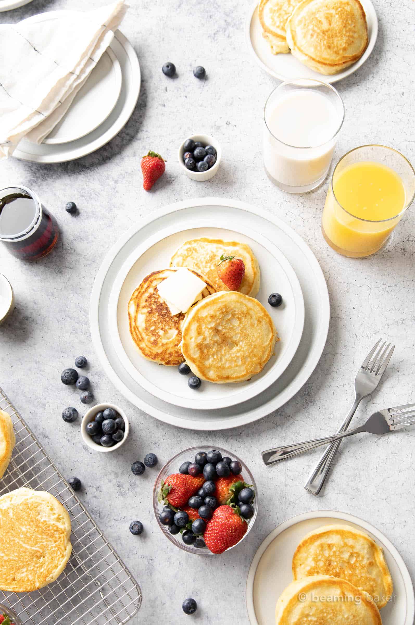 breakfast table with fluffy vegan pancakes fresh fruit and orange juice