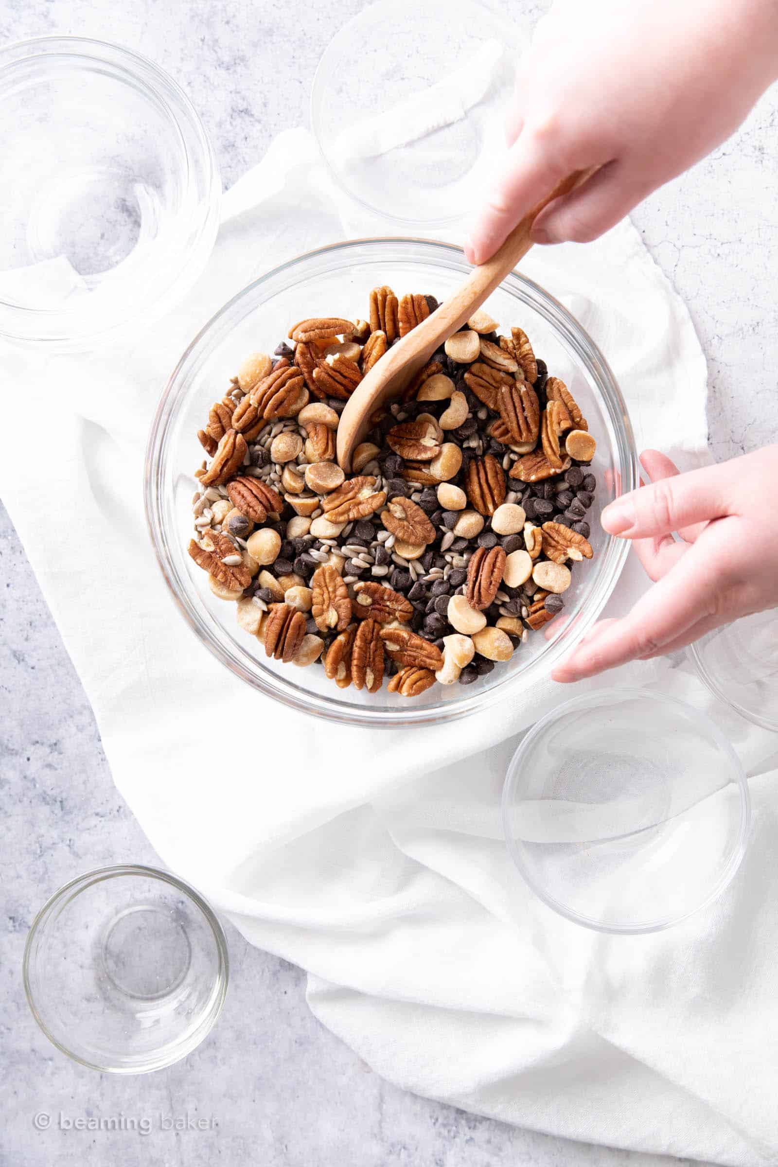 hand holding a wooden spoon mixing up keto friendly trail mix