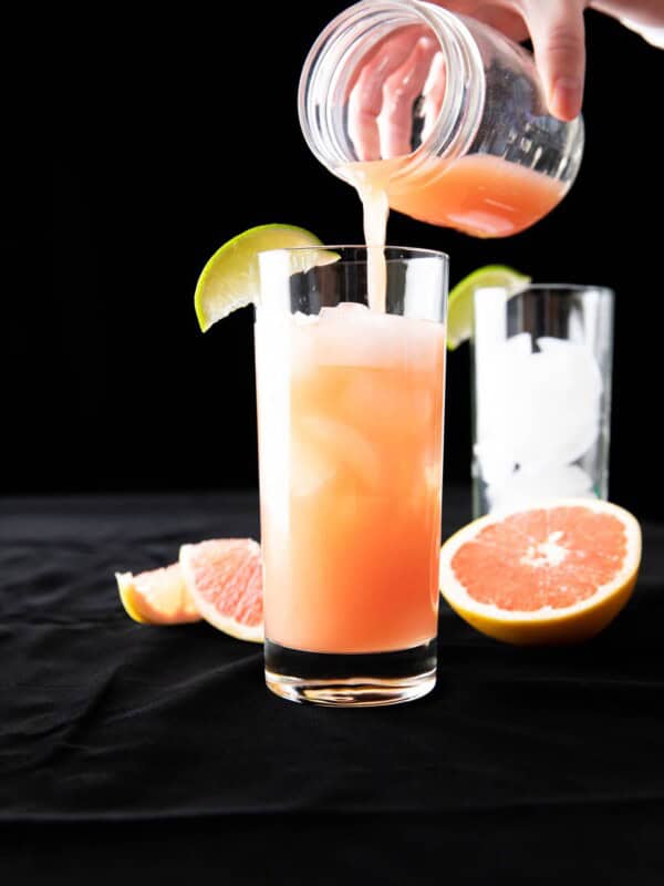 finishing the last pour of grapefruit juice into a glass to make a greyhound cocktail