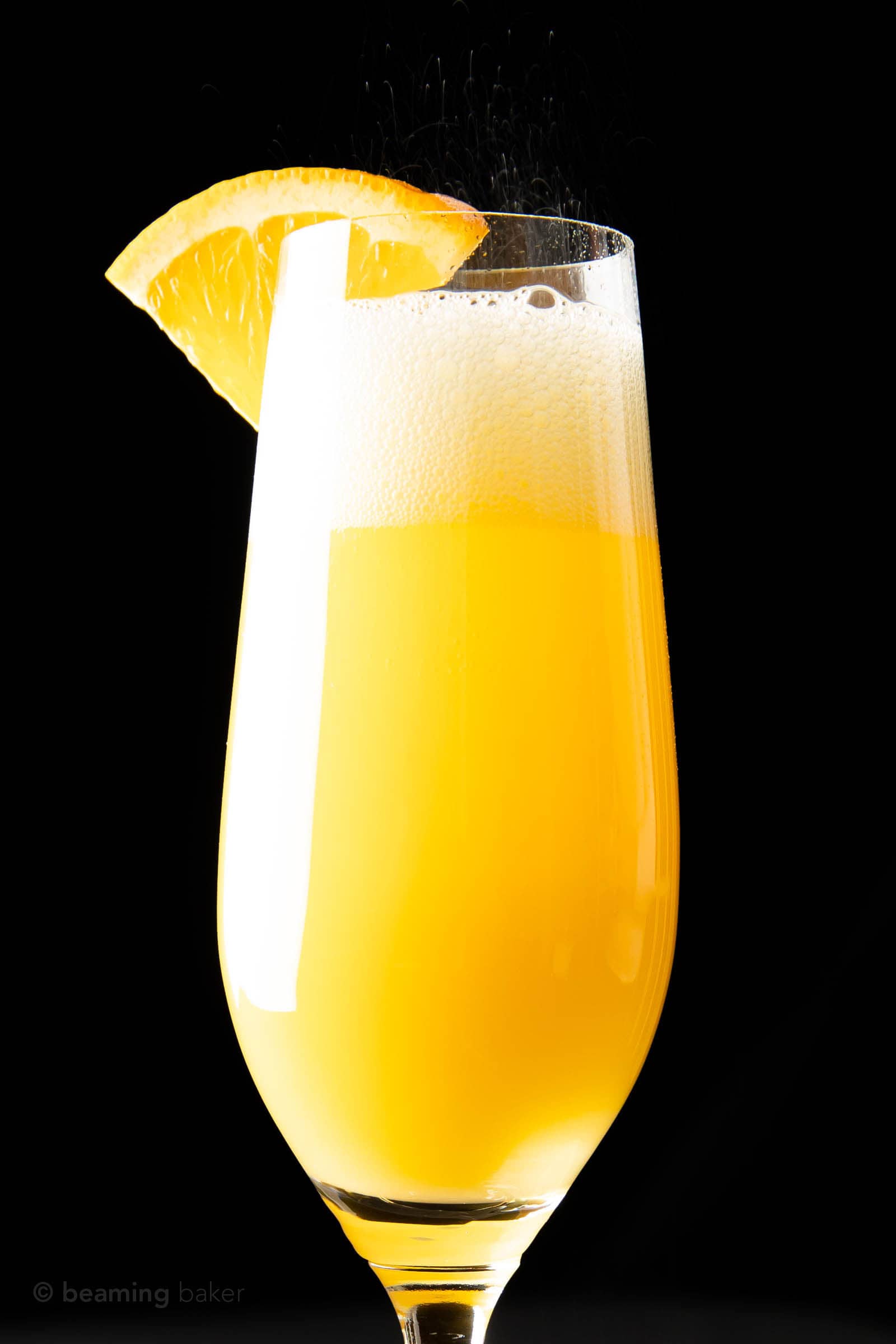 closeup of mimosa with prosecco fizzling bubbles out of the top of the champagne flute