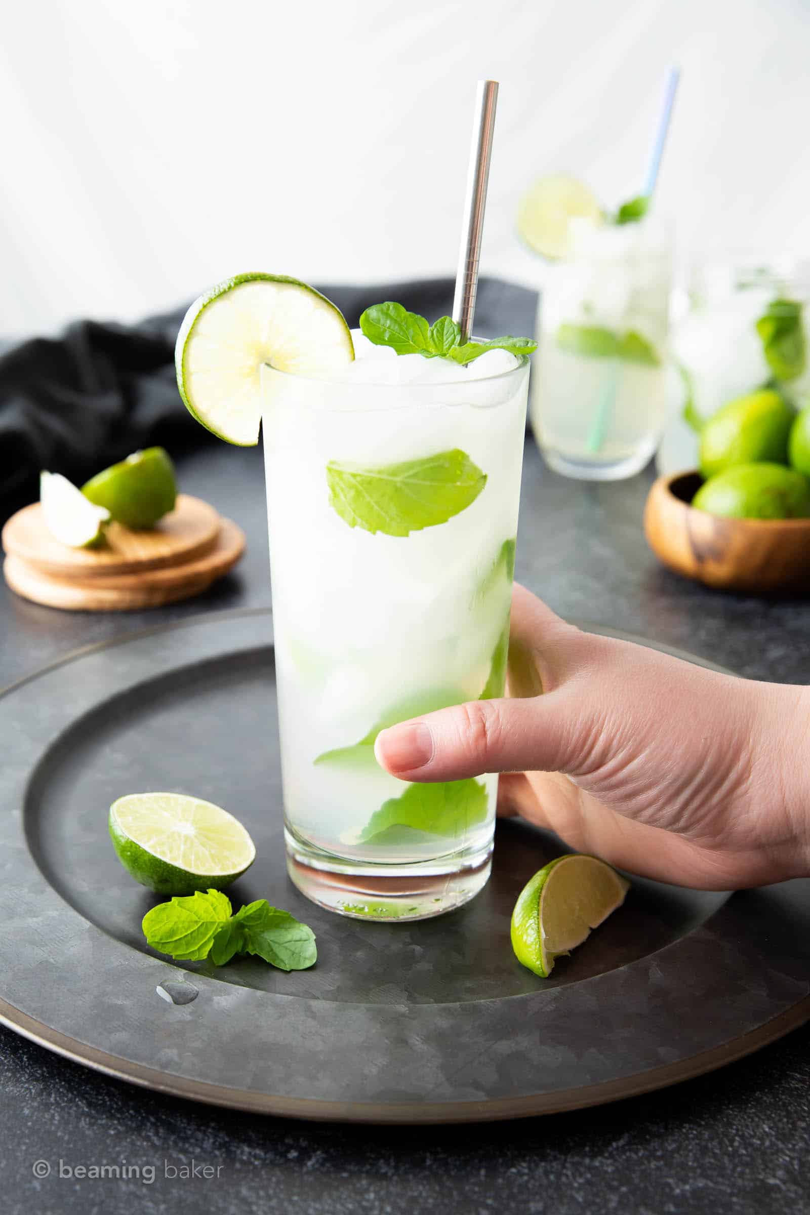 a hand grabbing a glass of a freshly made classic mojito recipe