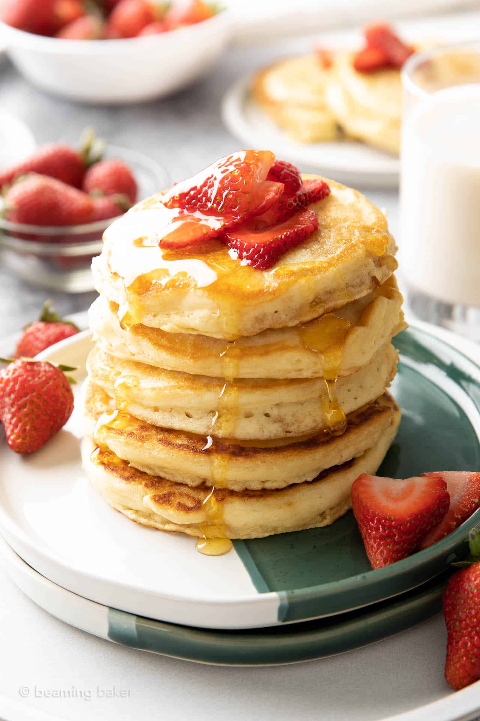pancake syrup drizzling down strawberry pancakes in a tall stack