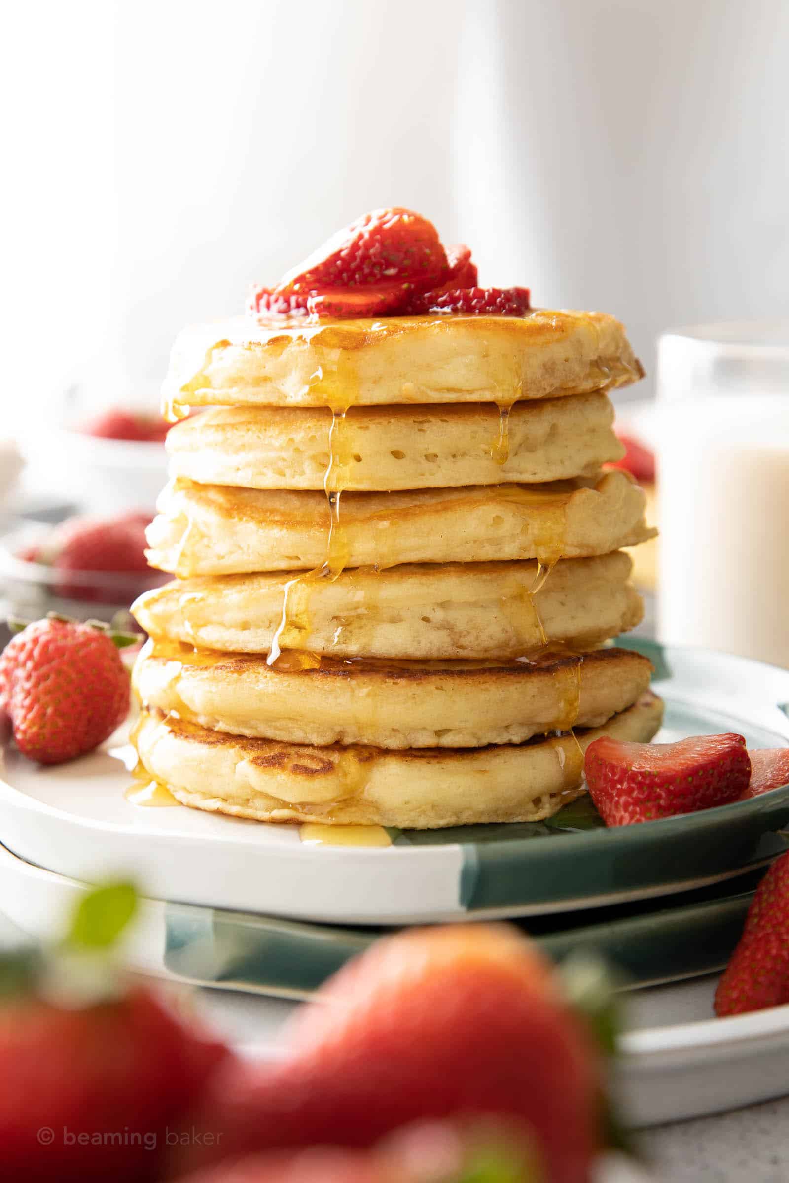 fluffy pancakes topped with strawberries and served with fresh whole strawberries