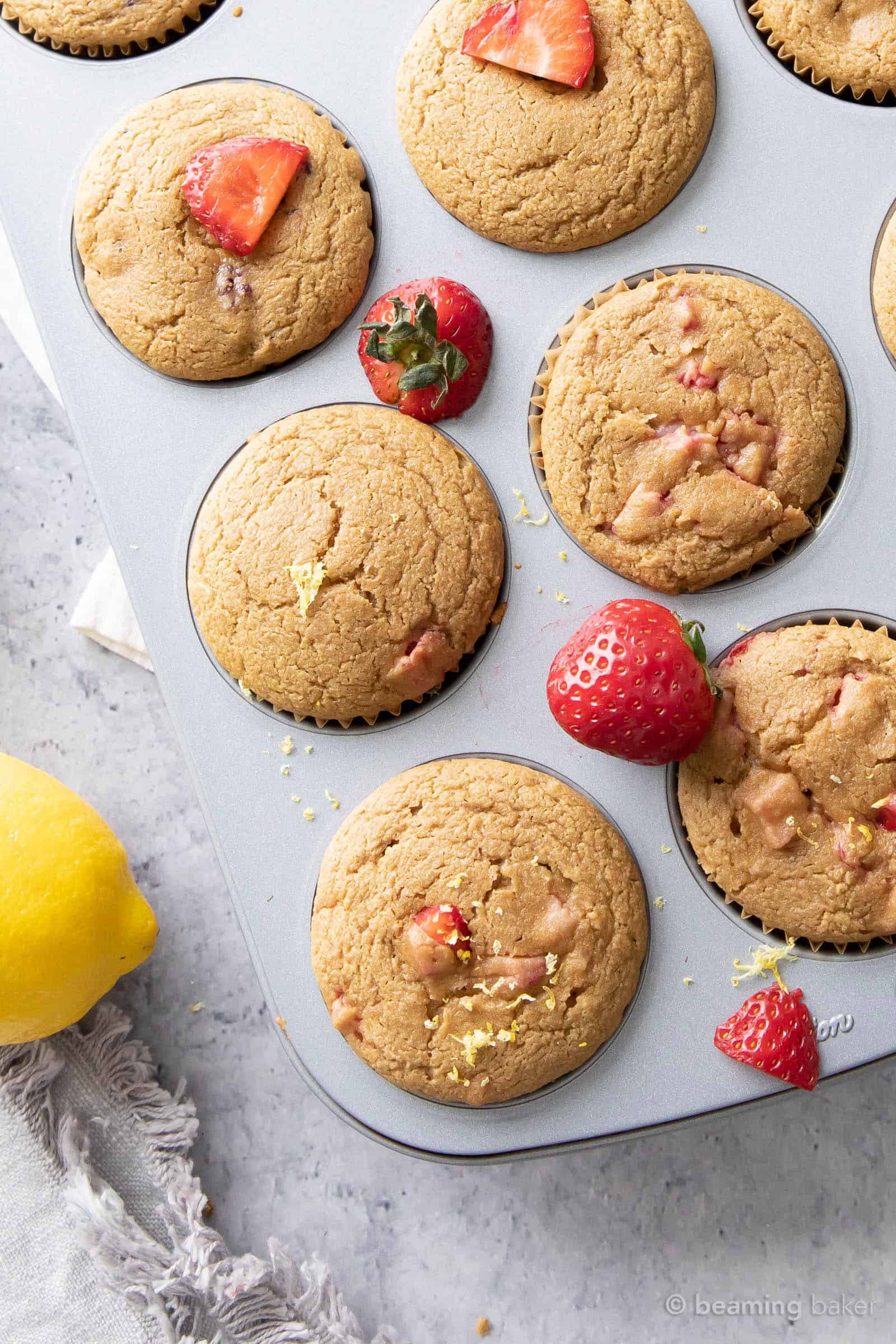 closeup shot of finished strawberry lemon muffin recipe with slices of strawberries and whole lemons and napkins