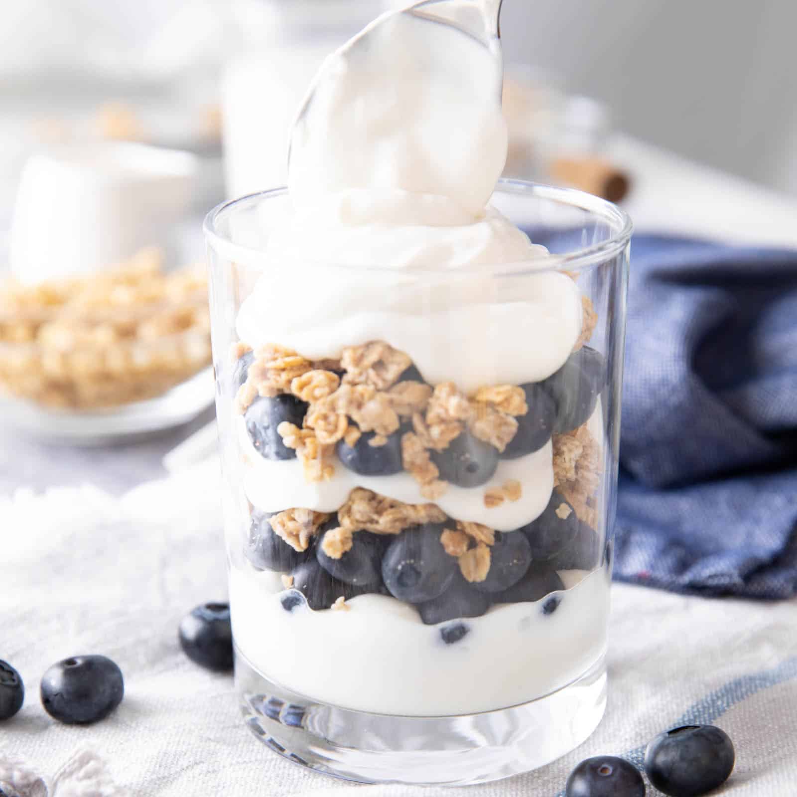 Creating the final layer of yogurt in the blueberry yogurt parfait in square image