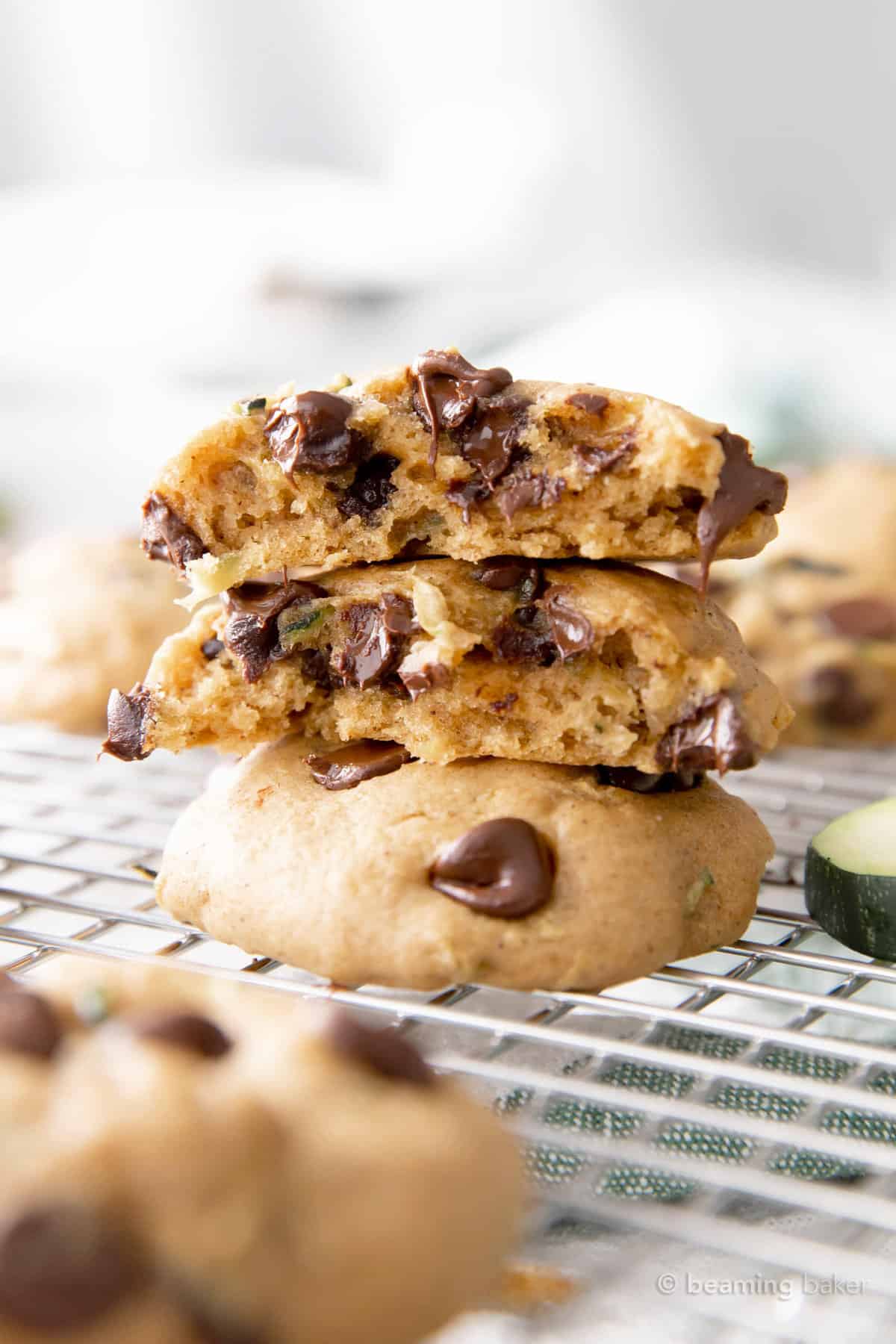 Three fresh-baked zucchini chocolate chip cookies in a stack on a silver cooling rack