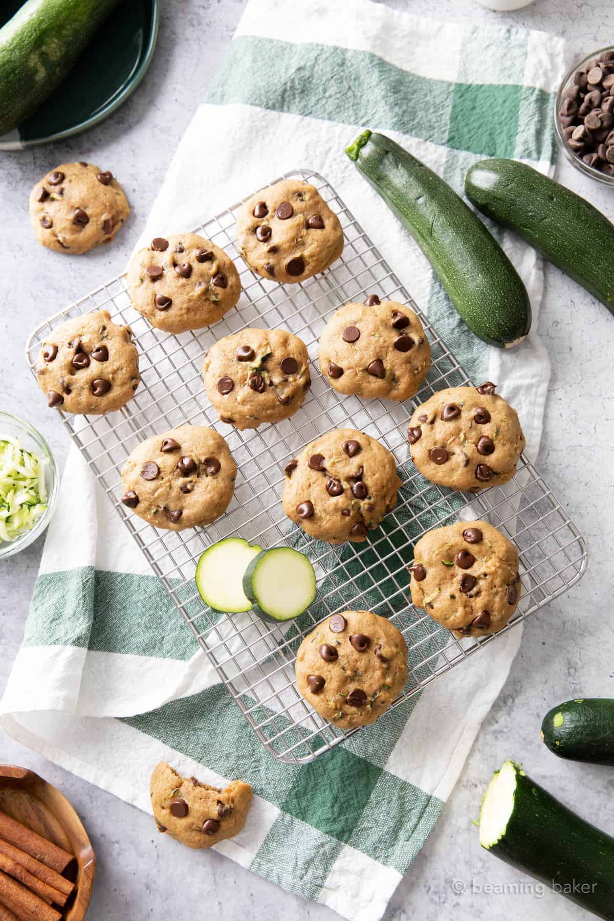 Overhead shot of chocolate chip zucchini cookies on a kitchen table with fresh zucchinis