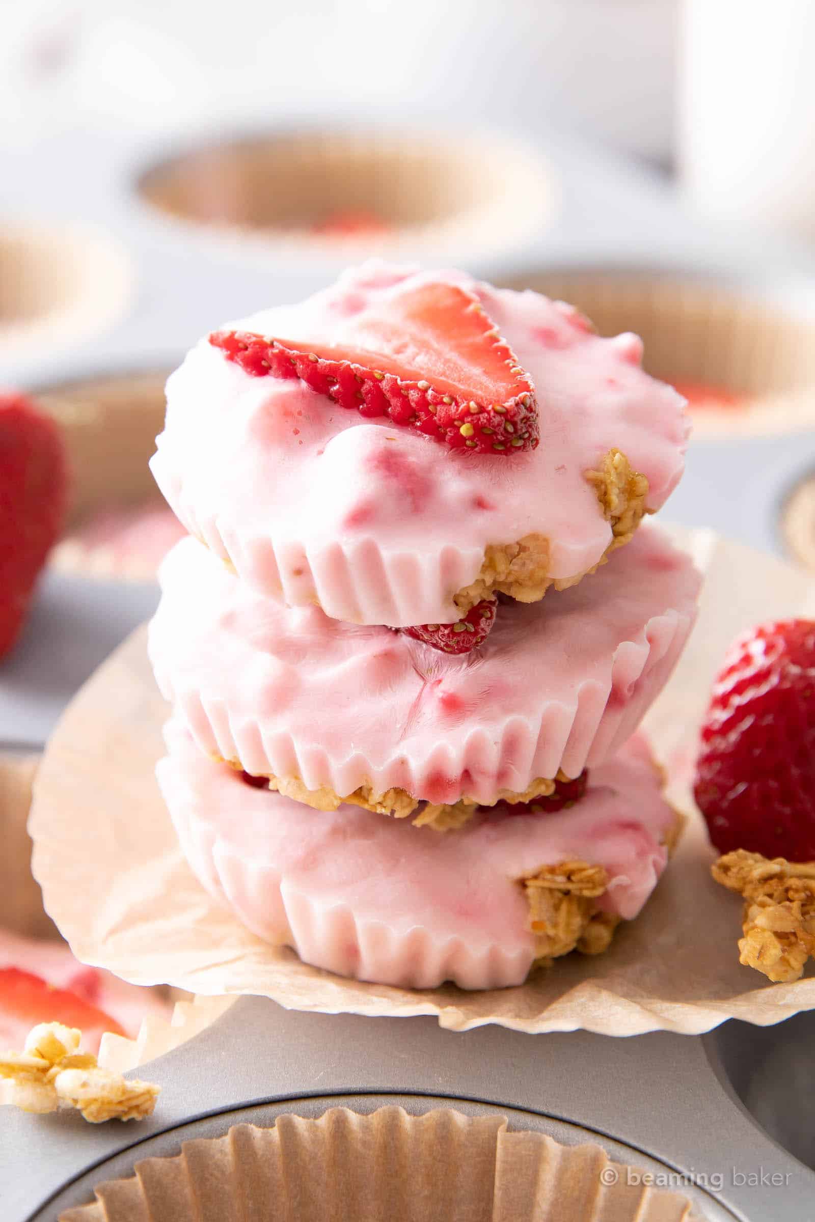 stack of strawberry yogurt bites on an unfolded cupcake liner with a fresh strawberry