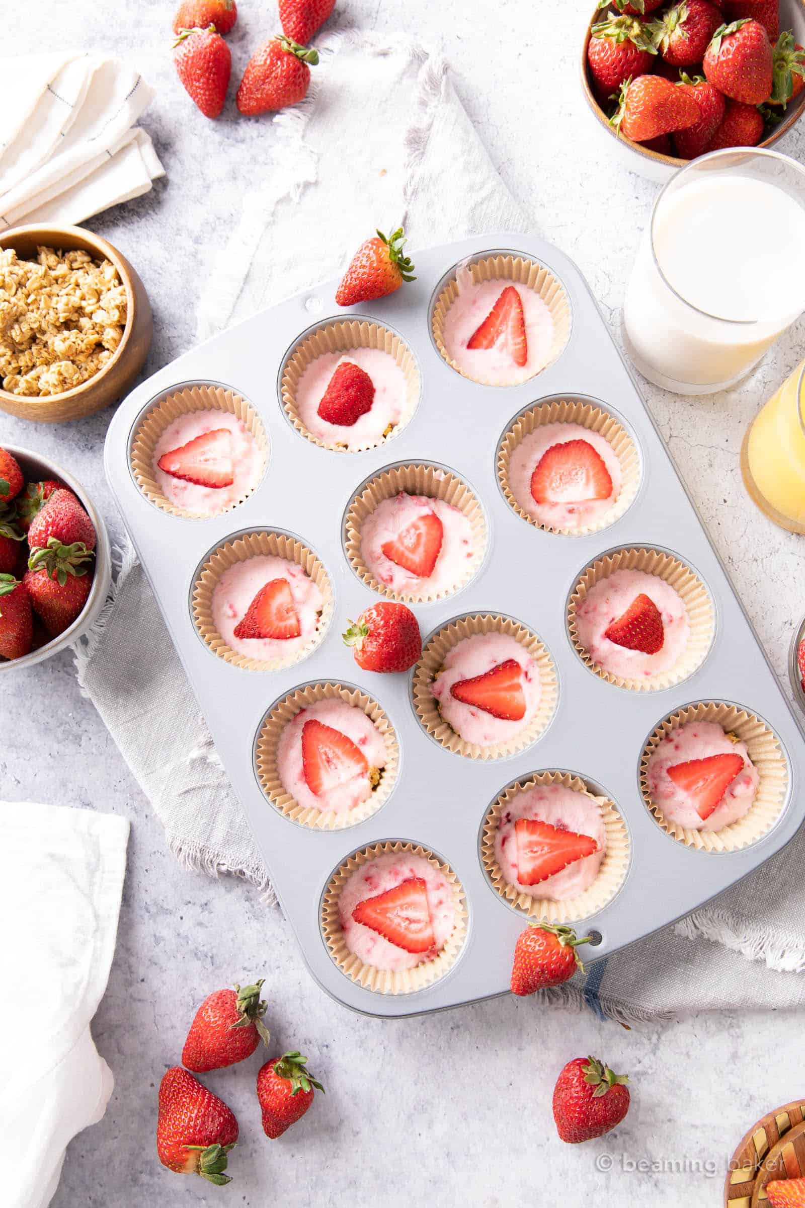 marble breakfast table with a tray of strawberry yogurt bites, bowl of granola, fresh strawberries and juice