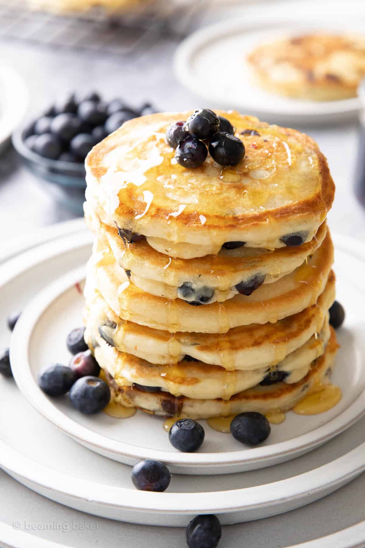 Tall stack of vegan blueberry pancakes drenched in syrup