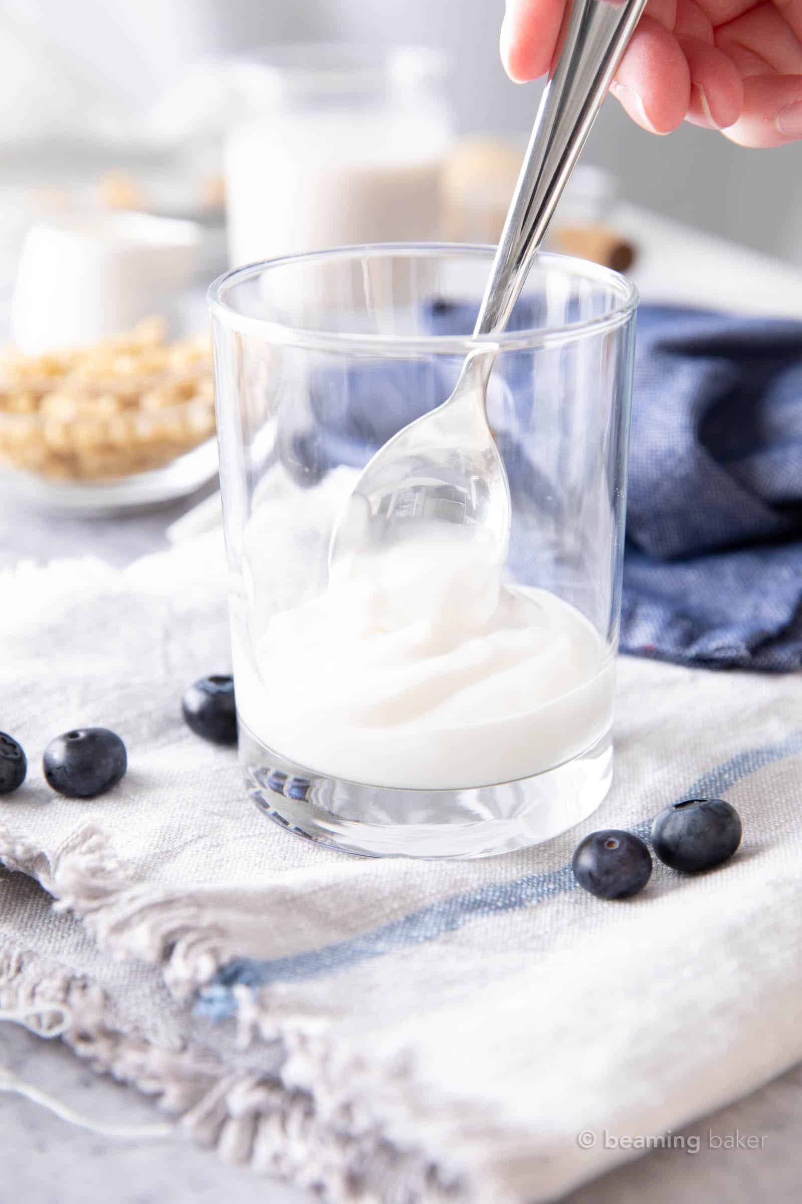 spooning yogurt into a glass for the blueberry parfait