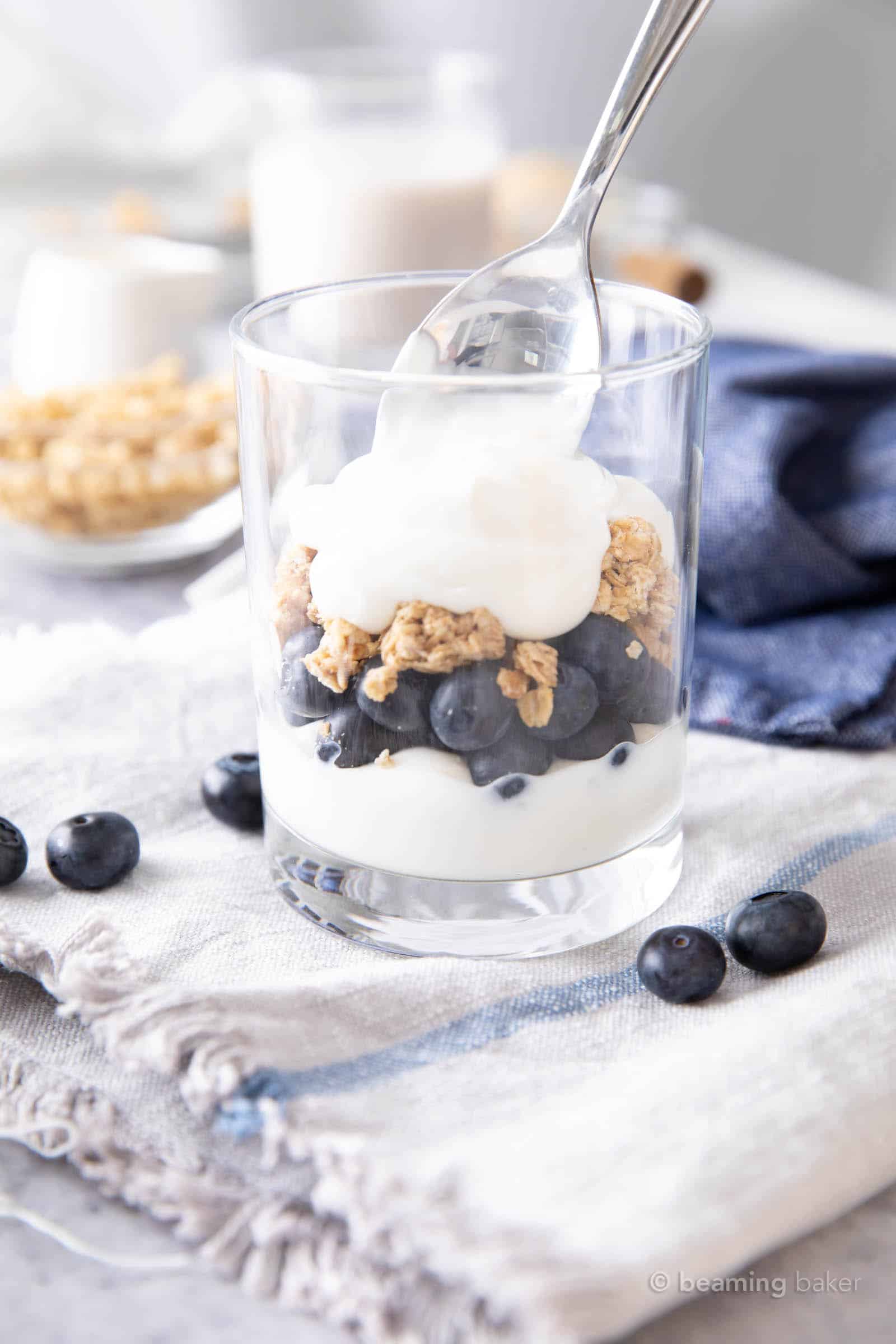 Spooning yogurt over the blueberry and granola layers in the blueberry parfait