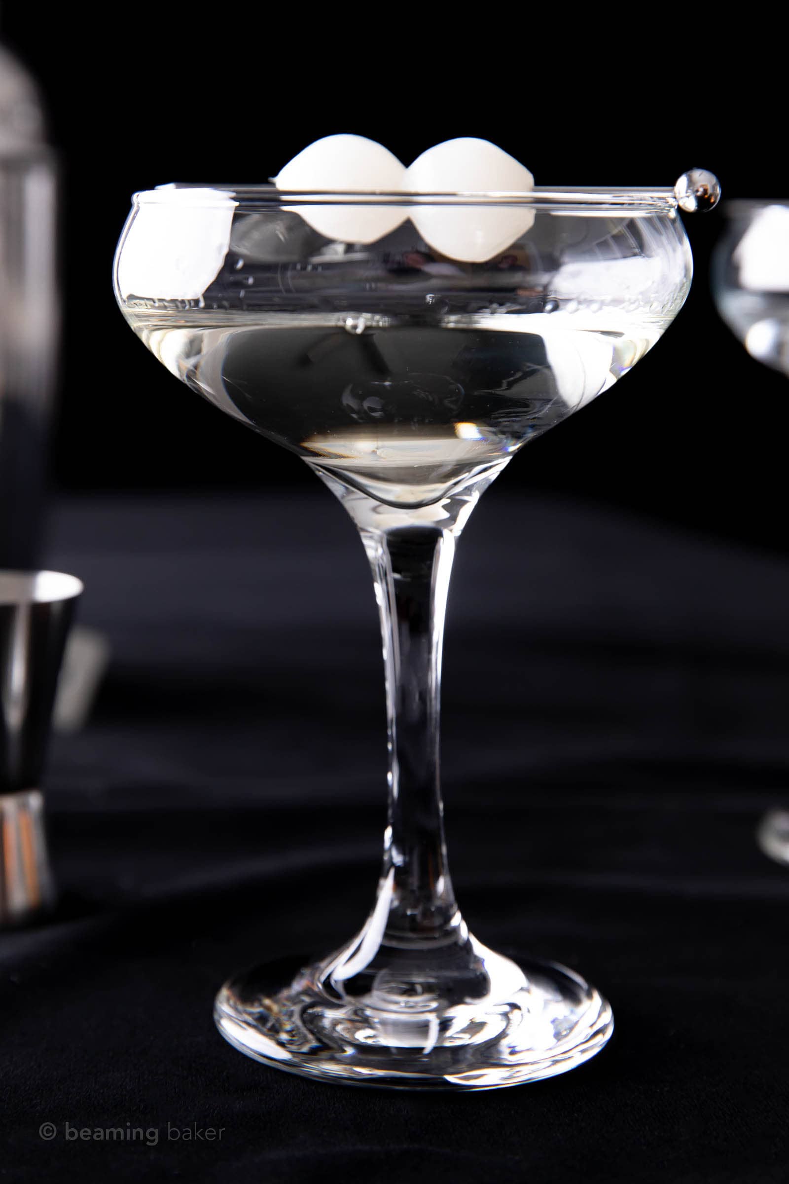 side view of the gibson drink recipe in a coupe glass on a black backdrop