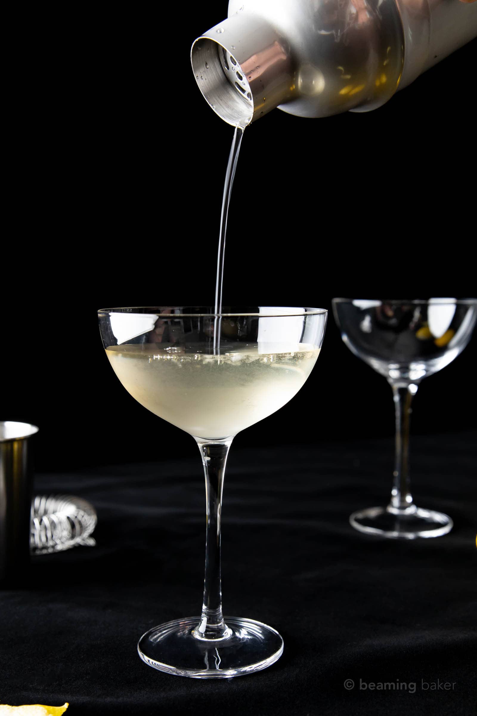 50 50 martini recipe being pouring from a stainless steel cocktail shaker into a half-filled glass