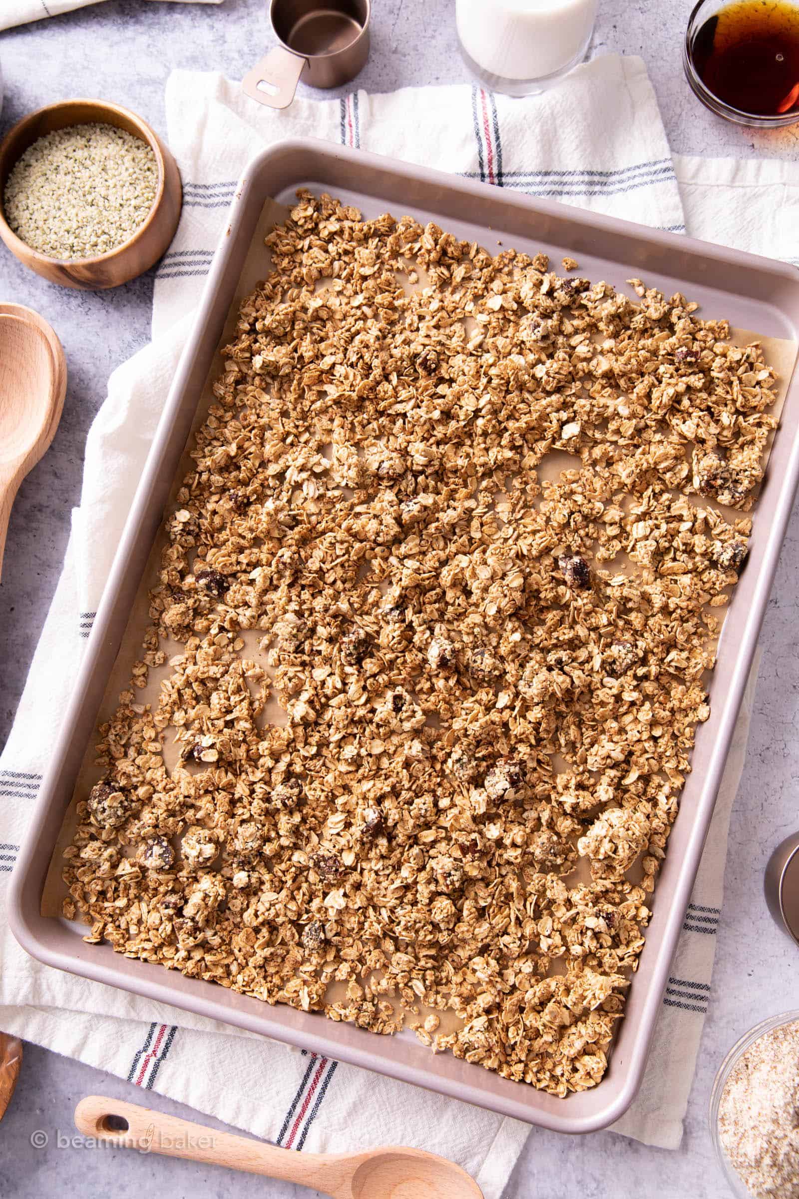 rose gold baking sheet filled with hemp granola on a plaid kitchen cloth
