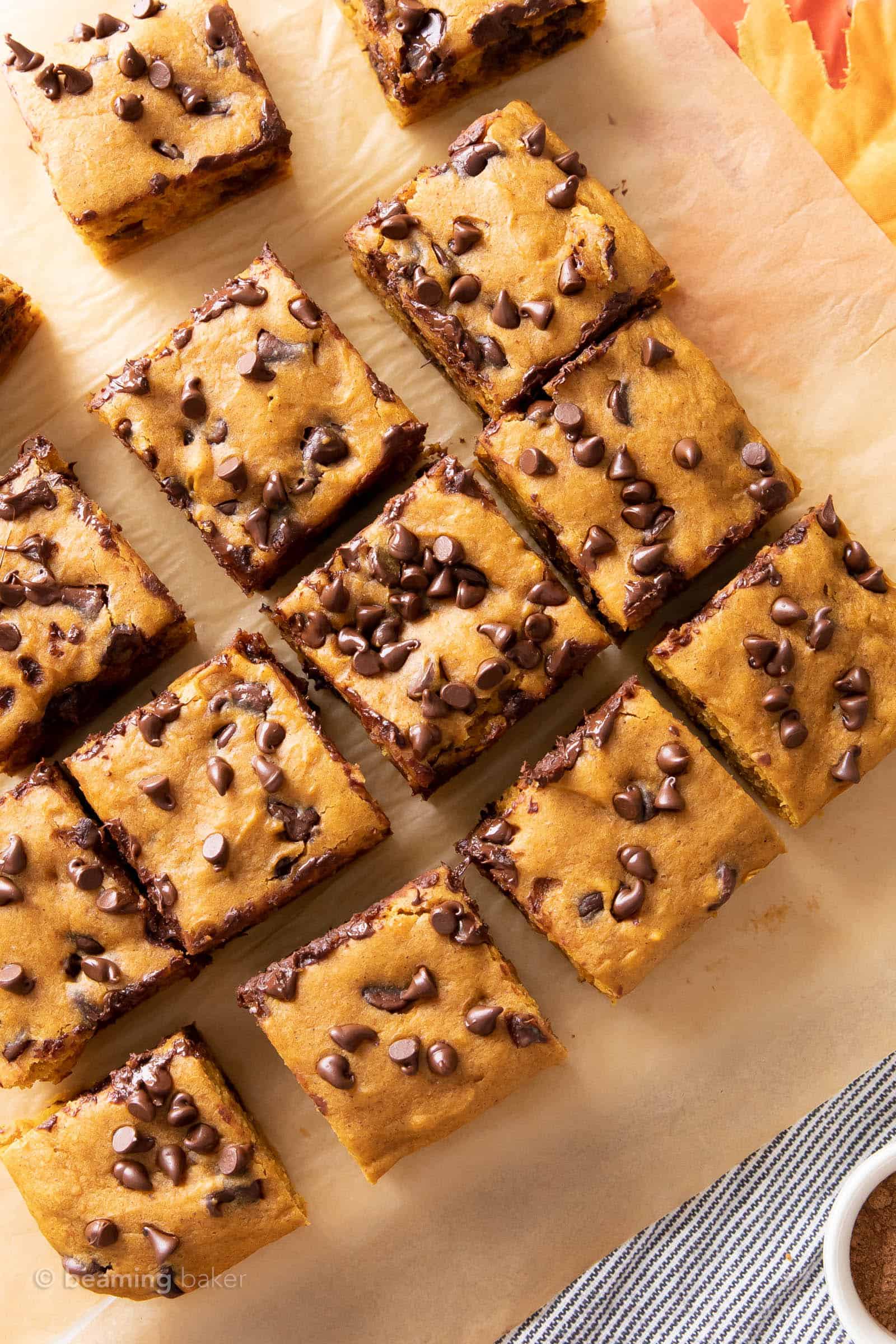 gluten free pumpkin chocolate chip bars against a brown backdrop with a bowl of pumpkin pie spice