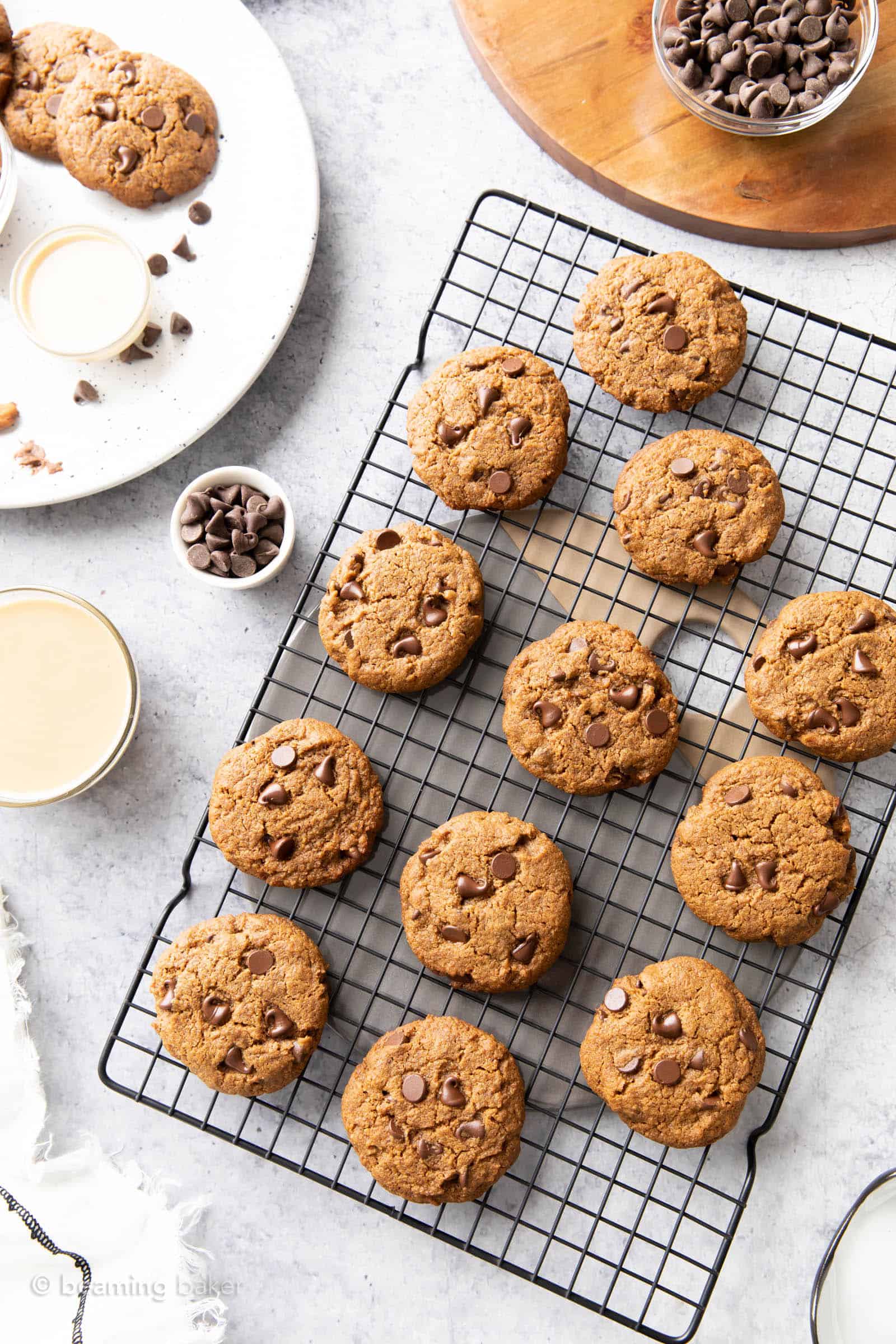 A black cooling rack topped with fresh baked chocolate chip tahini cookies on a kitchen table