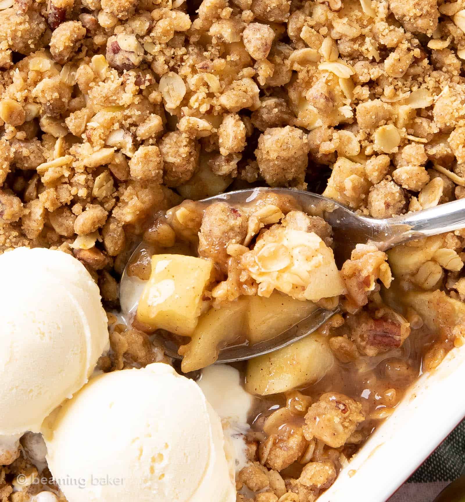 gooey apples peaking out from under brown sugar oat crumble topping on a spoon