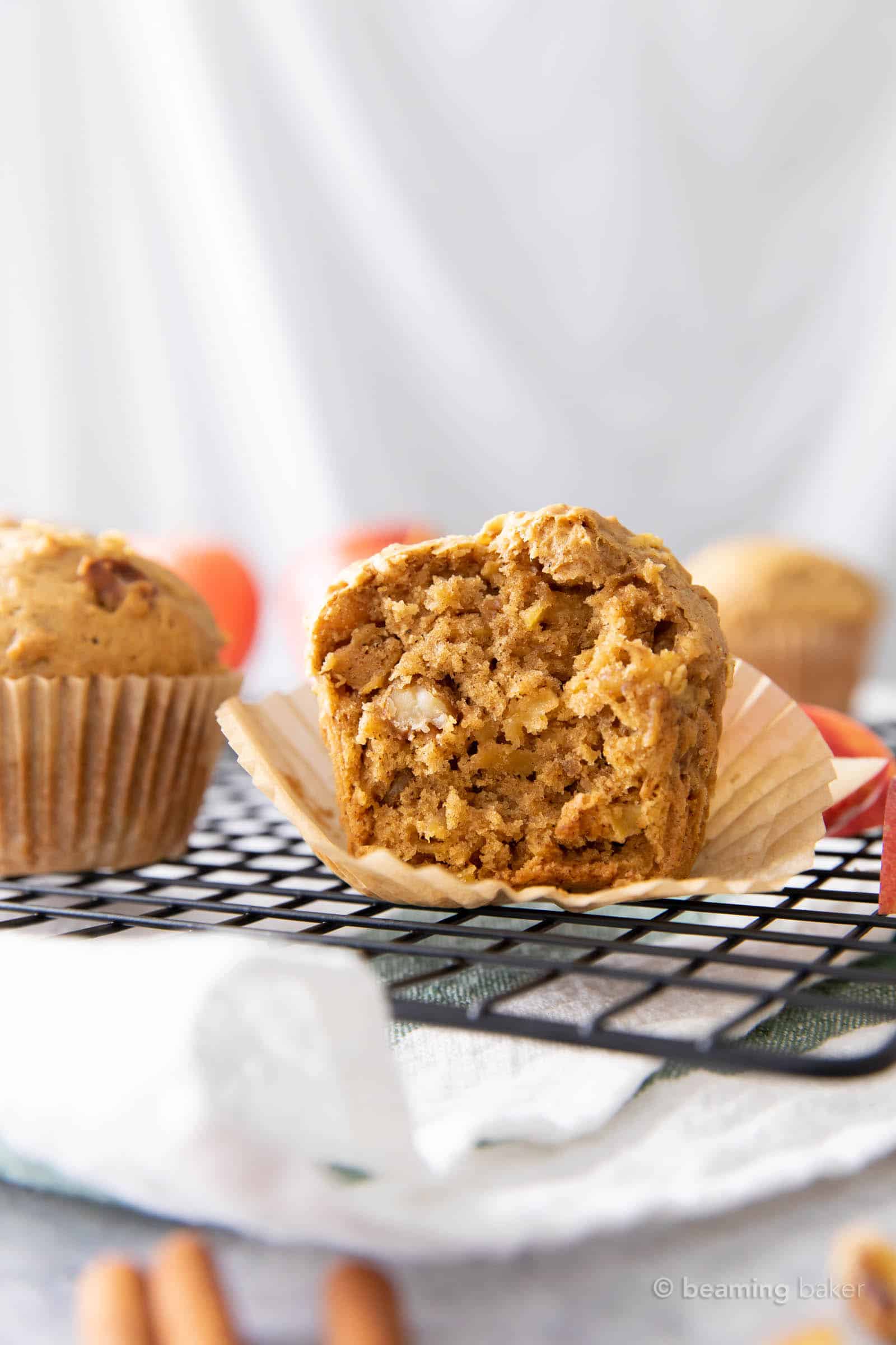 Half of an apple muffin on a parchment muffin liner