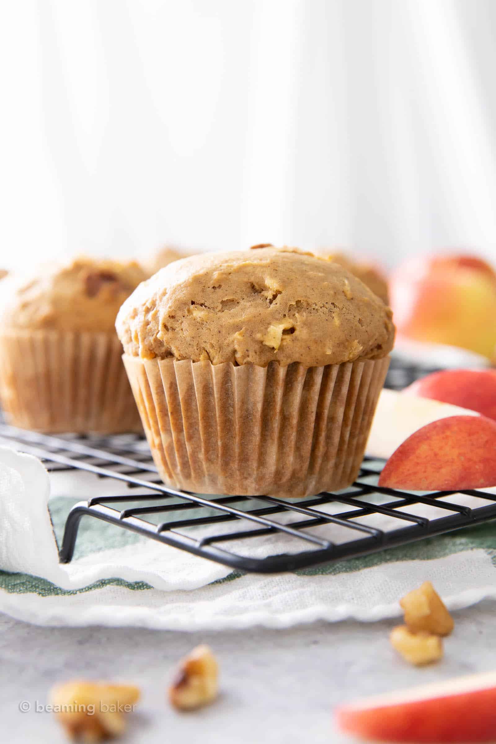 black cooling rack filled with fresh baked vegan apple cinnamon muffins and apple slices