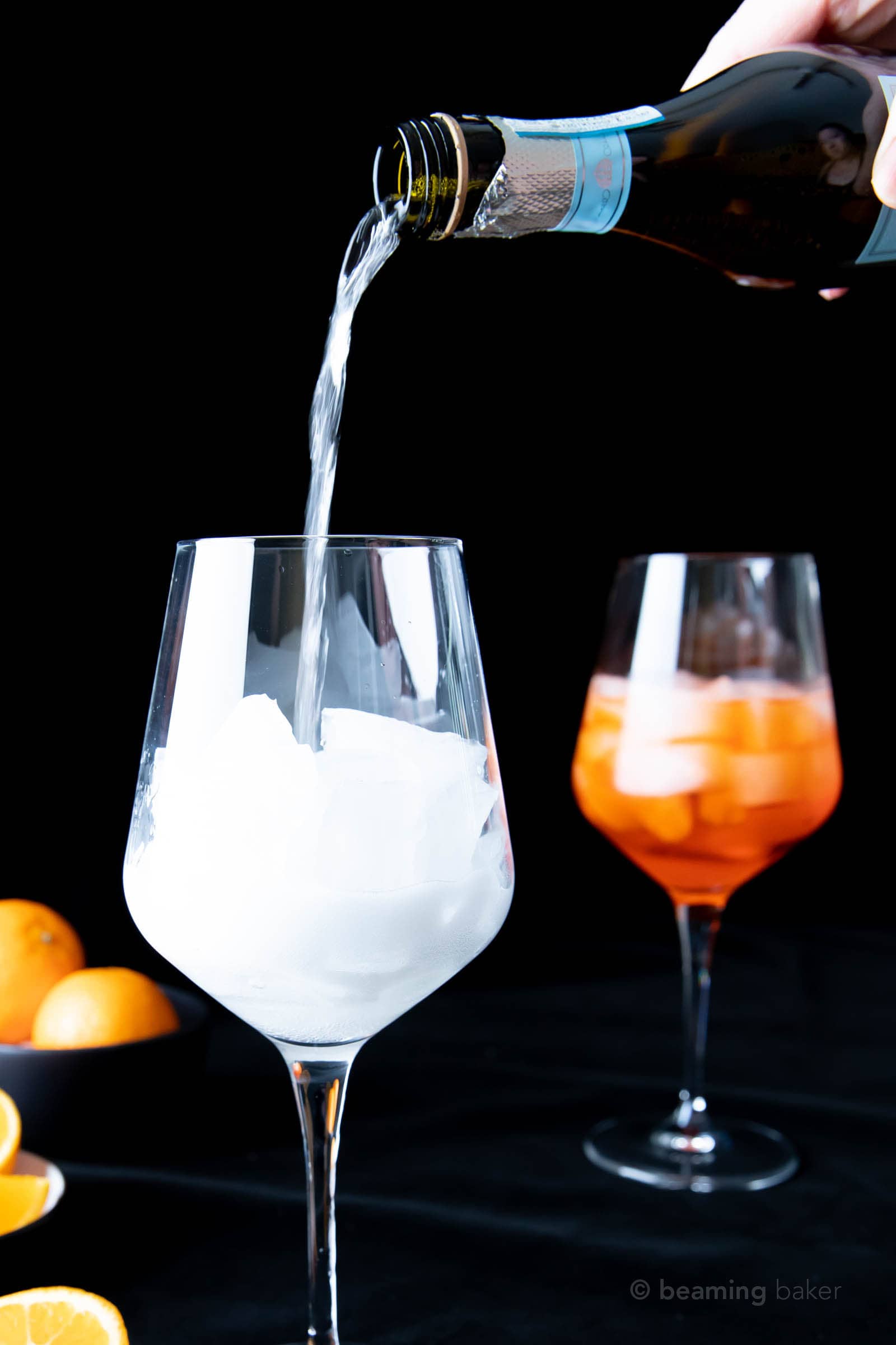 hand pouring Prosecco into wine glass filled with ice