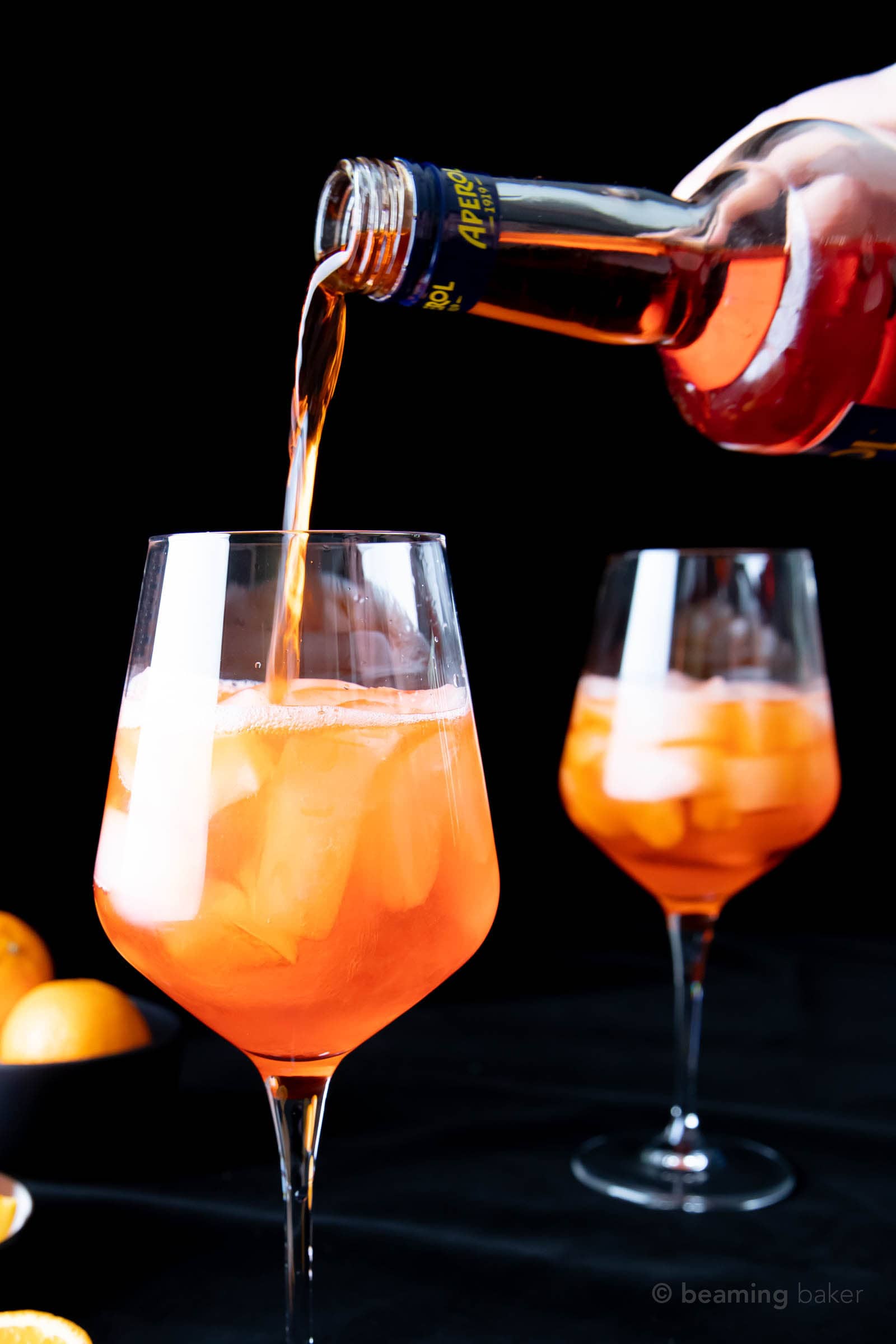 Pouring more Aperol into glass, filling it more than halfway for Aperol Spritz