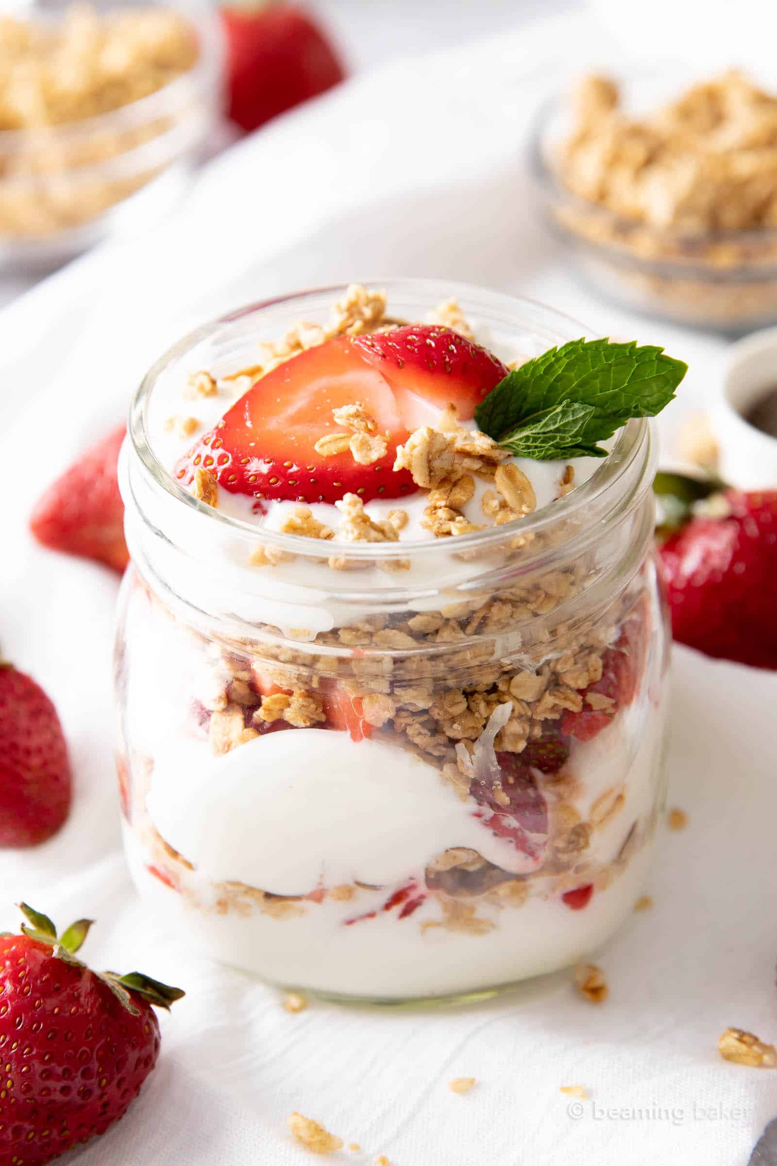 closeup shot of strawberry yogurt parfait with granola and fresh strawberries on a white kitchen towel