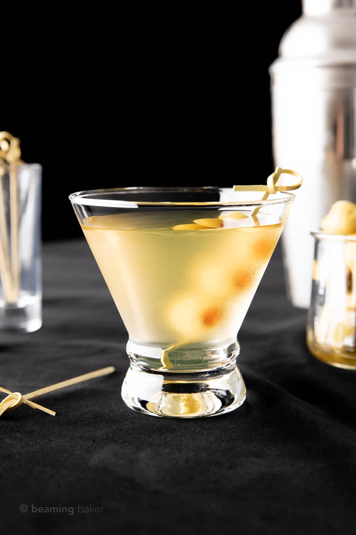 A short martini glass filled with extra dirty martini with a bamboo skewer