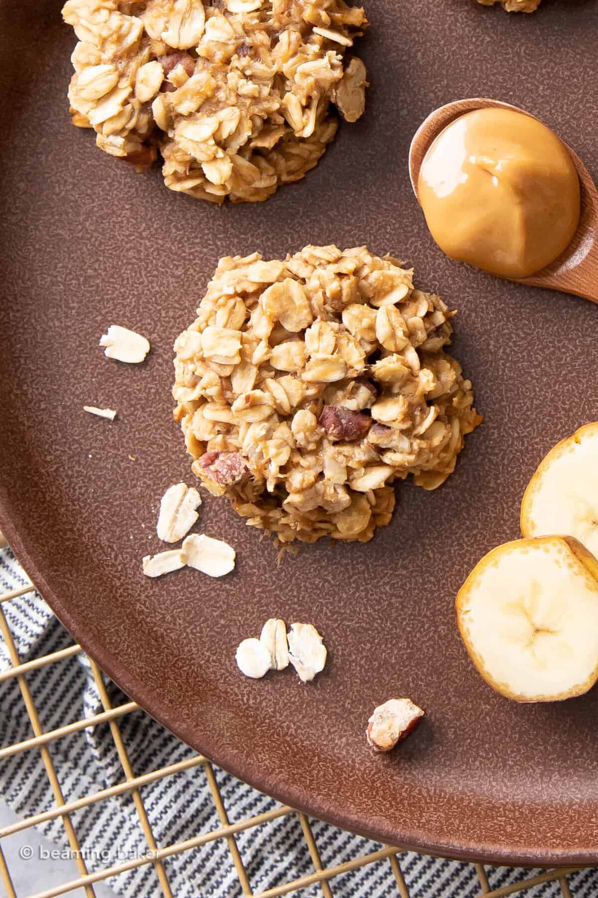 closeup of a 3 ingredient peanut butter banana cookie on a brown plate with oats