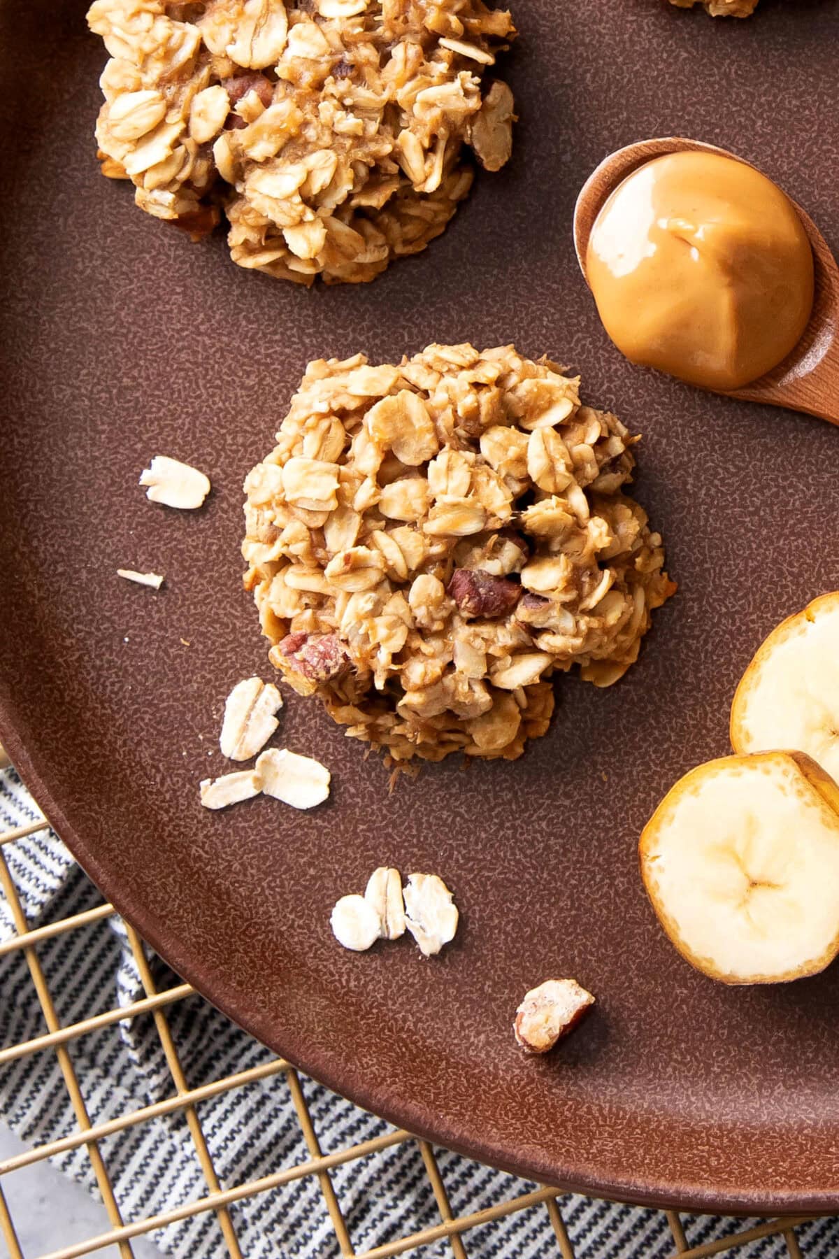 closeup of a 3 ingredient peanut butter banana cookie on a brown plate with oats