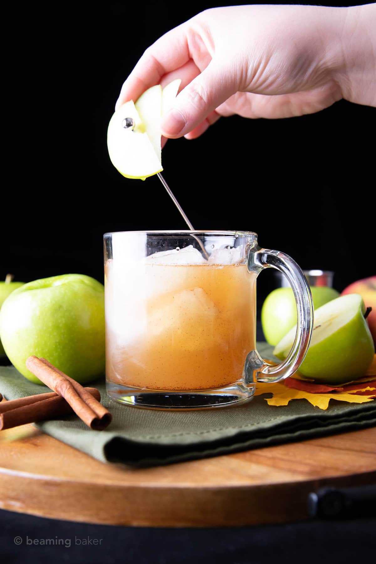 hand placing an apple skewer over drink