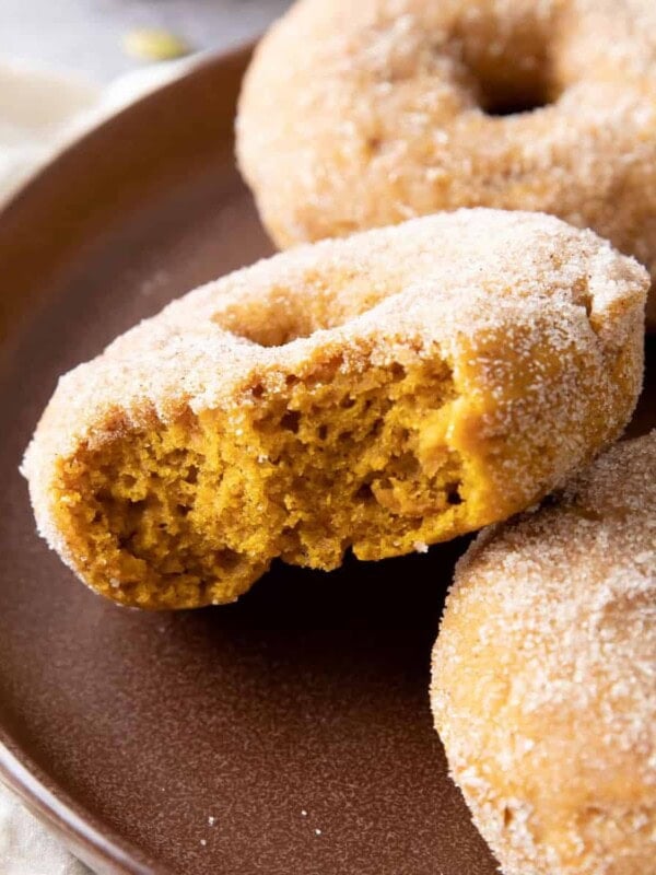 a bitten pumpkin donut on a brown plate