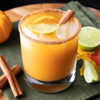 a pumpkin cocktail in a glass with a cinnamon stick