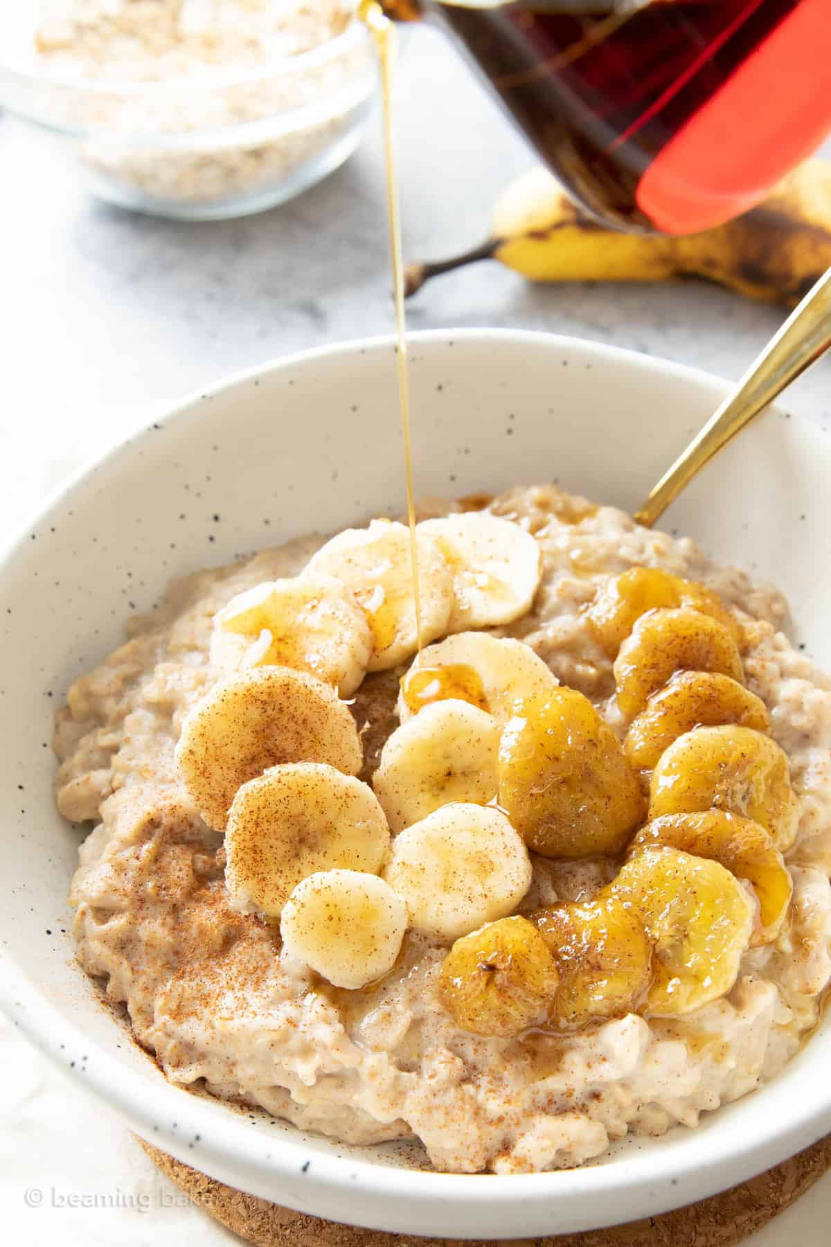 pouring maple syrup from a glass container over protein oatmeal