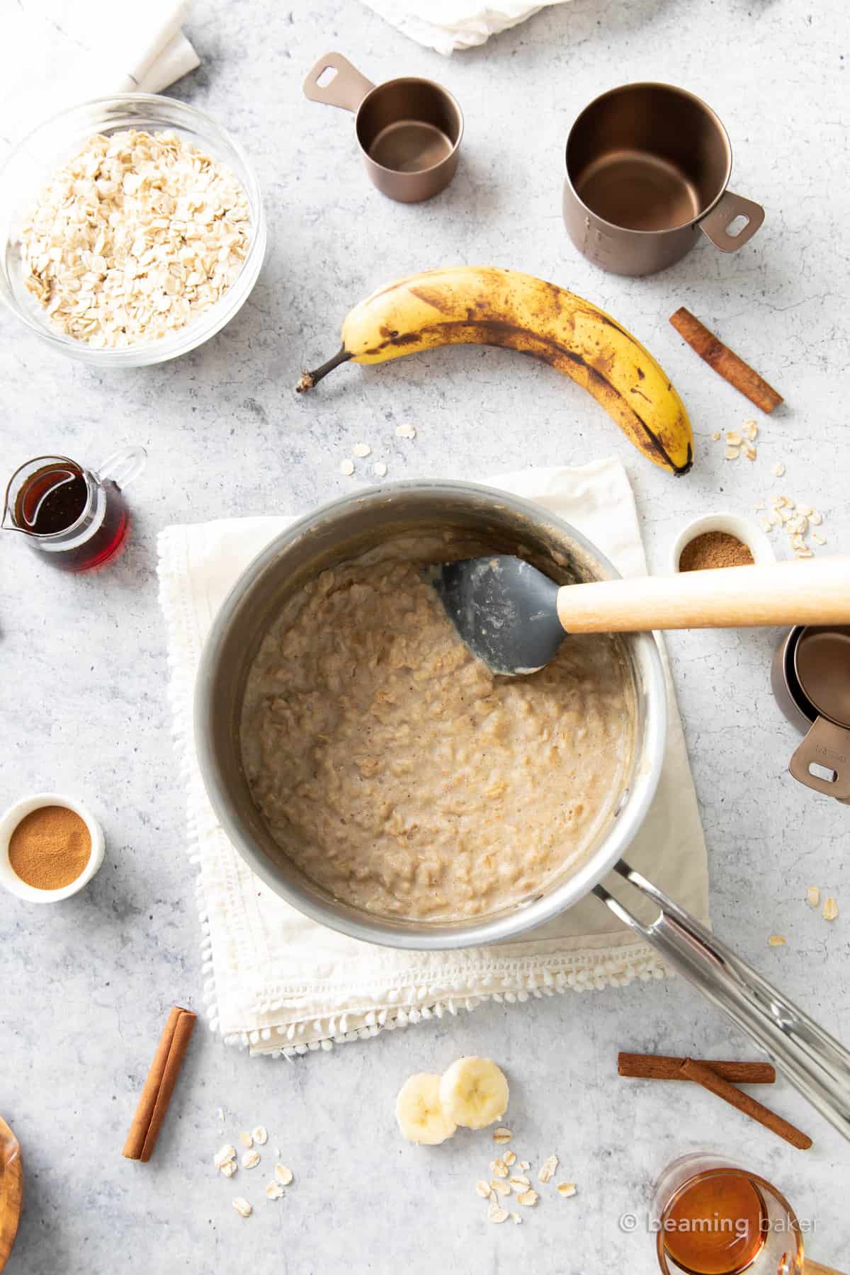 Wooden spatula stirring a pot of protein oatmeal on a cream cloth napkin