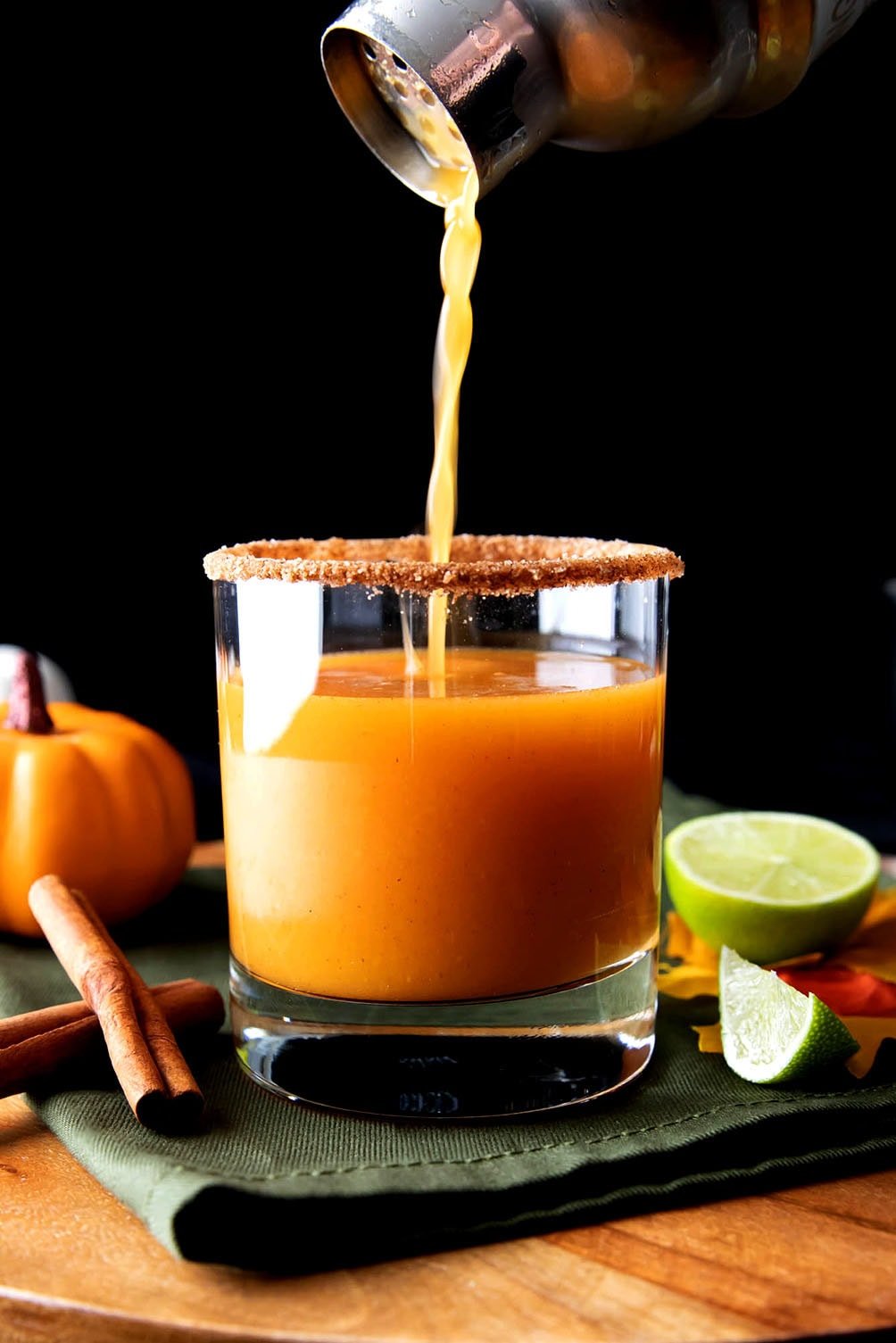 Pouring pumpkin cocktail made with pumpkin puree, pumpkin pie spice, lime juice, and tequila into a cocktail glass
