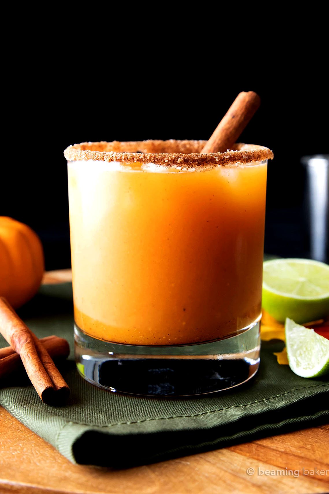 serving pumpkin cocktail packed with pumpkin flavors with a lime wedge and cinnamon stick