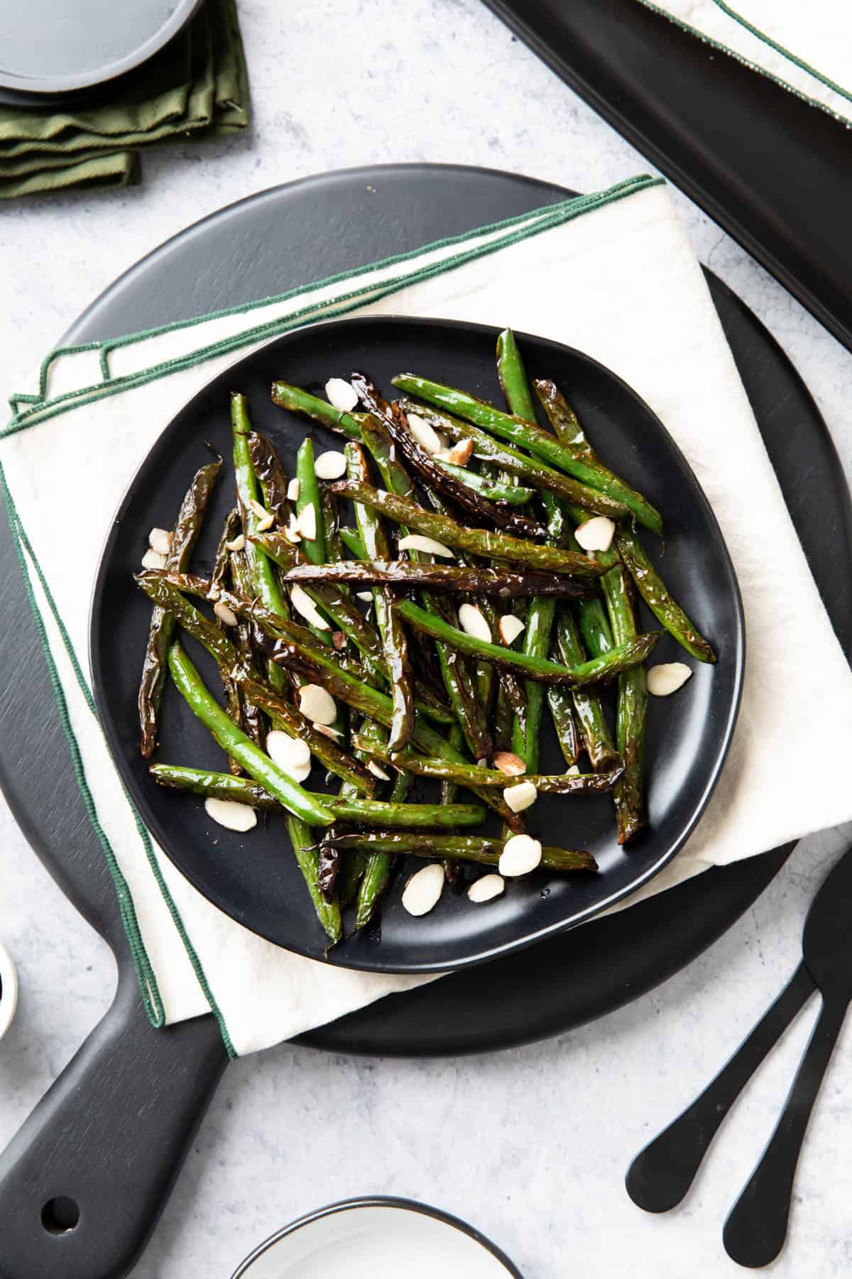 dining table with a black plate full of blistered green beans