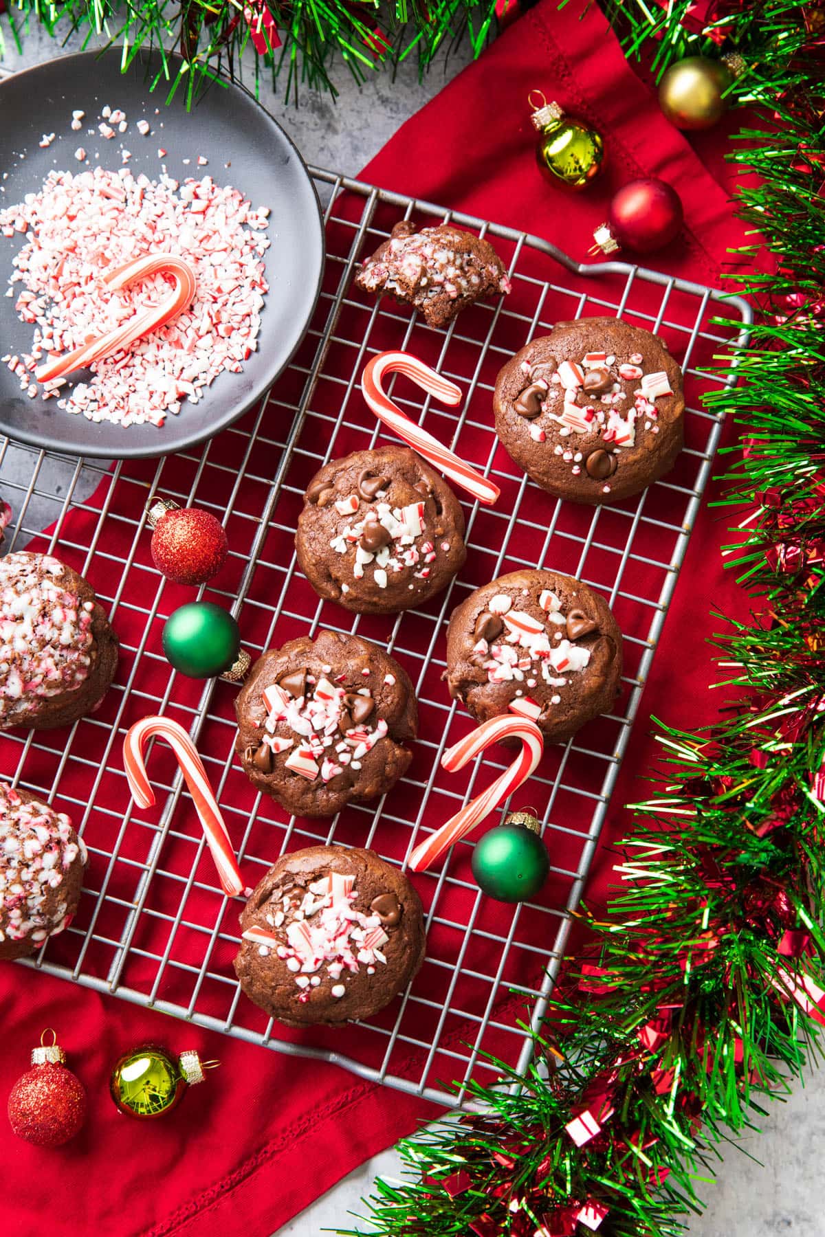 Fresh-baked easy chocolate peppermint cookies cooling on a rack with mini candy canes and Christmas decorations